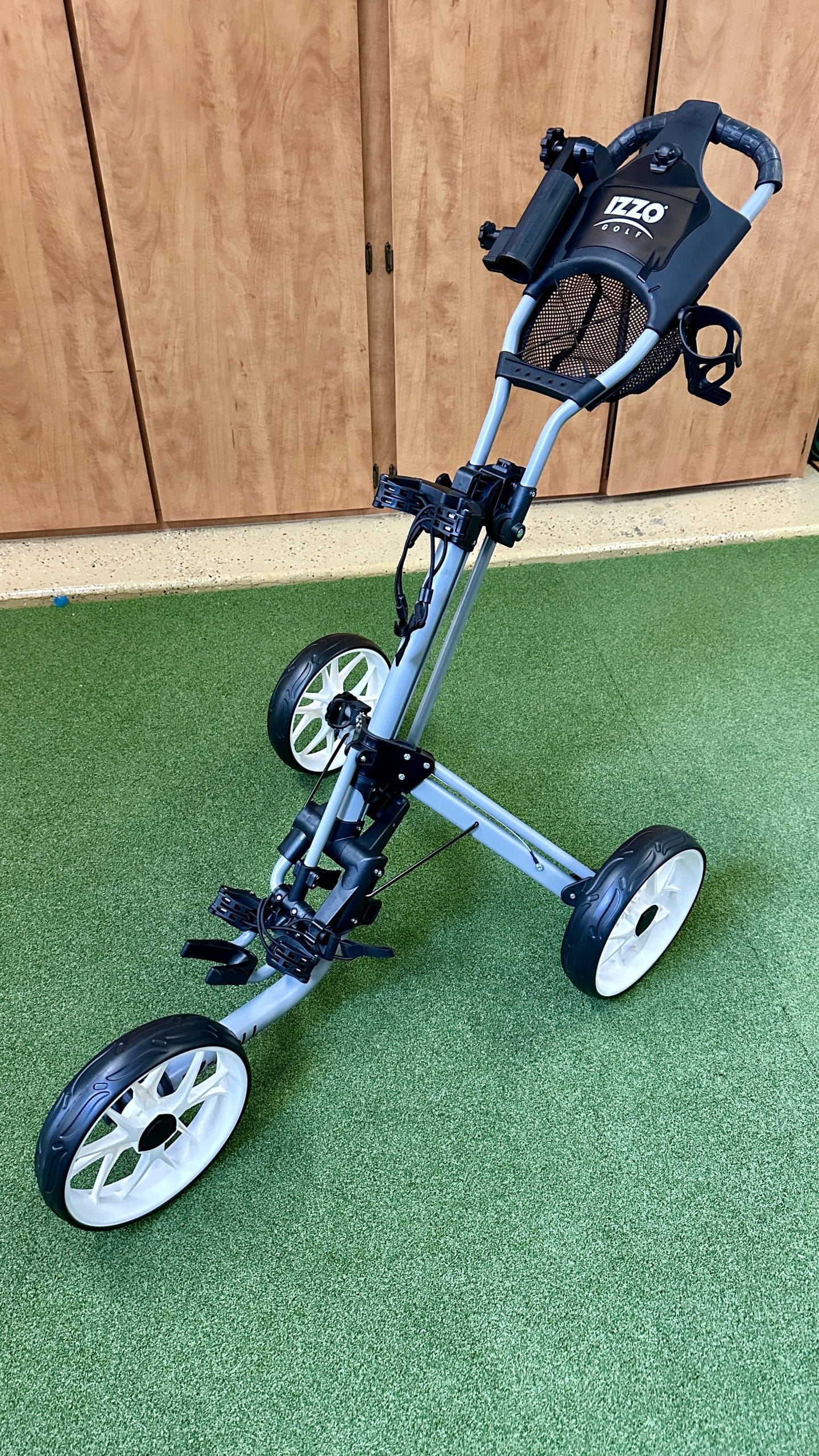 Foldable four-wheel golf push cart on green floor