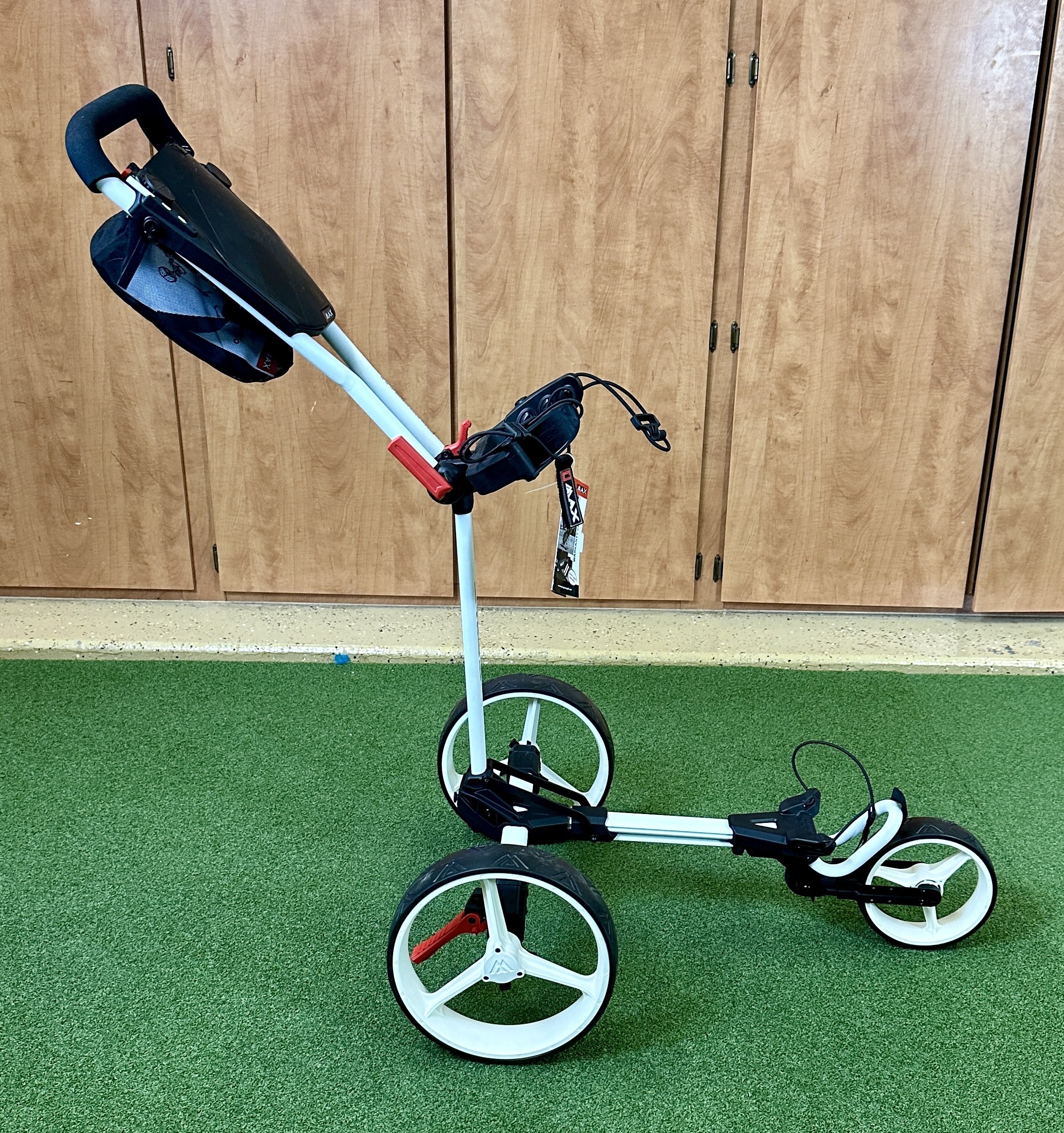 Three-wheel golf push cart on green turf