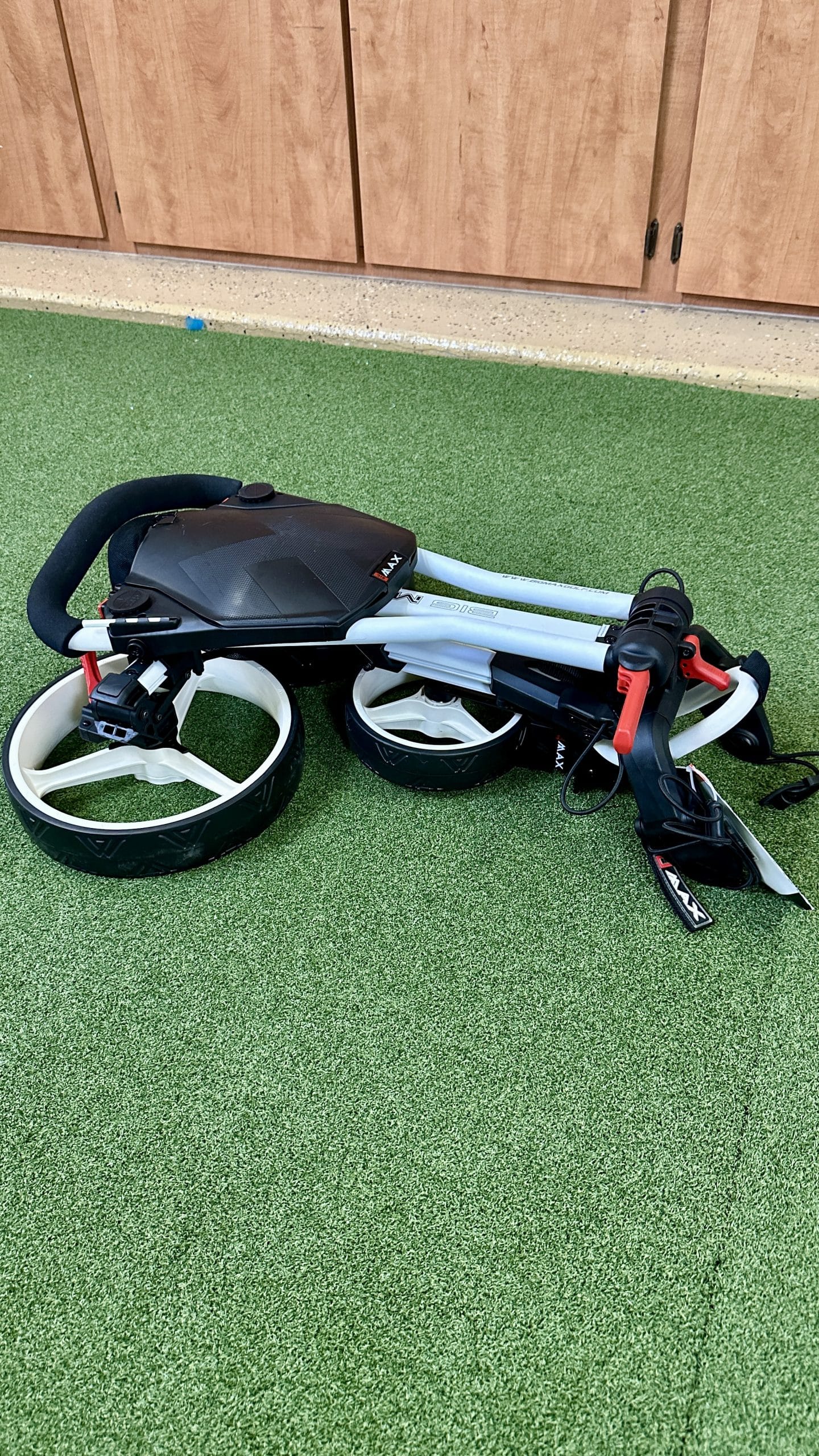 Folded golf push cart on green carpet