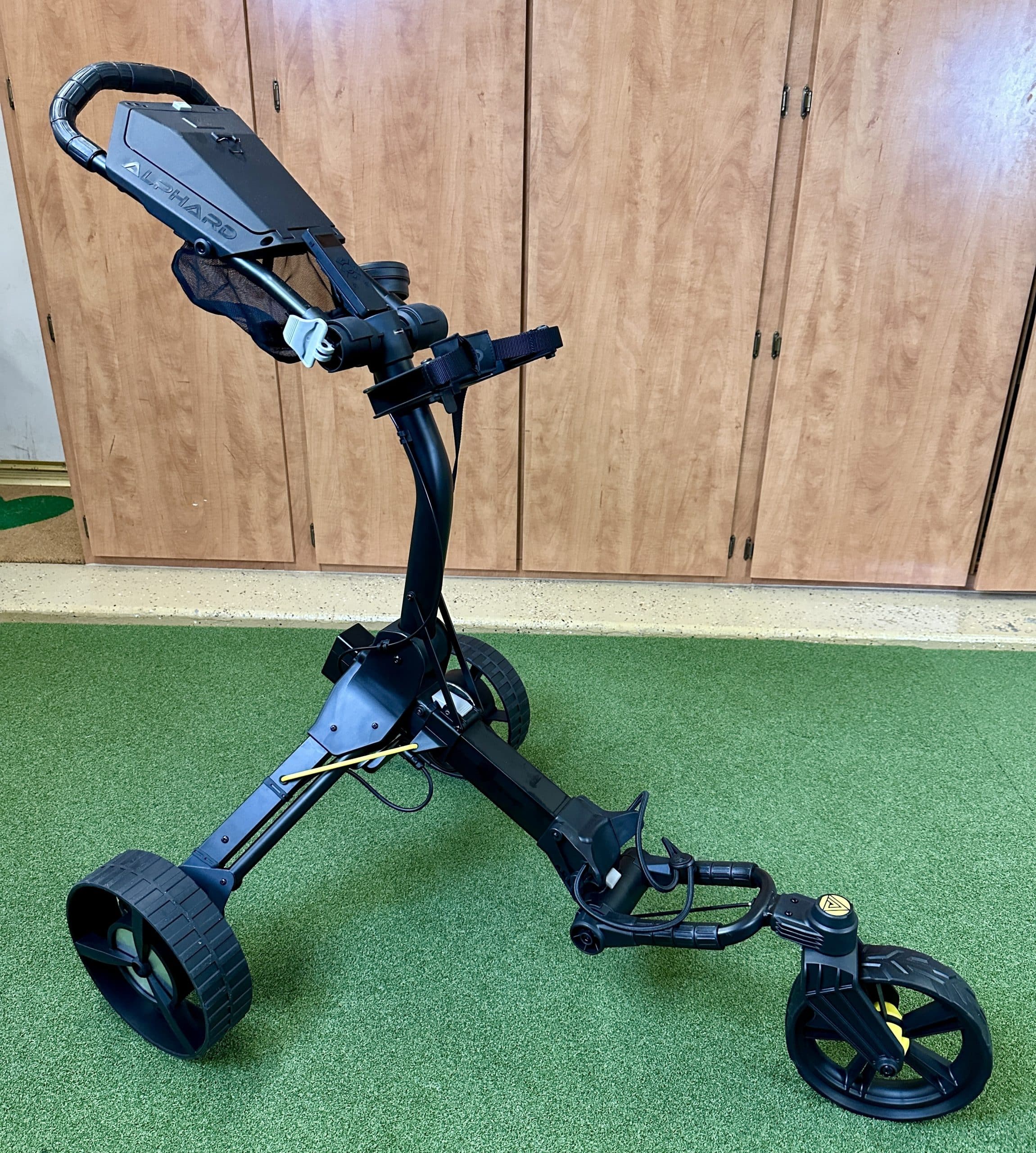 Black three-wheel electric golf push cart indoors