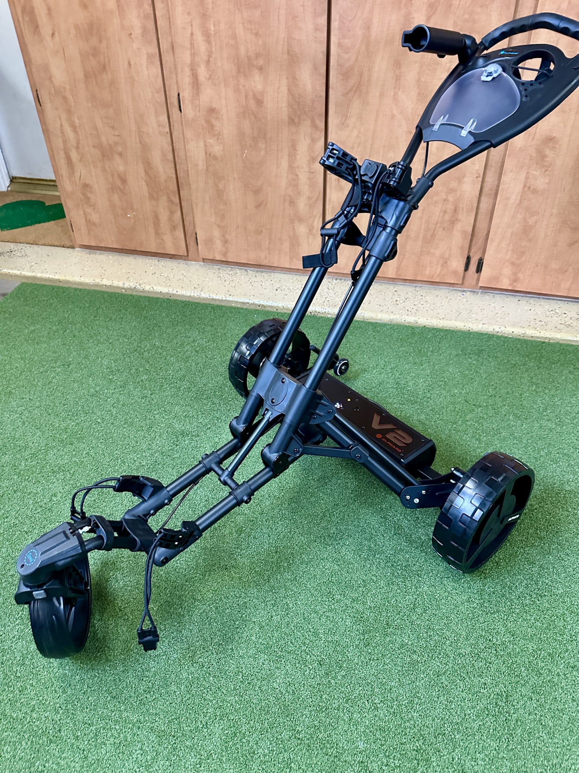 Black electric golf push cart on green turf