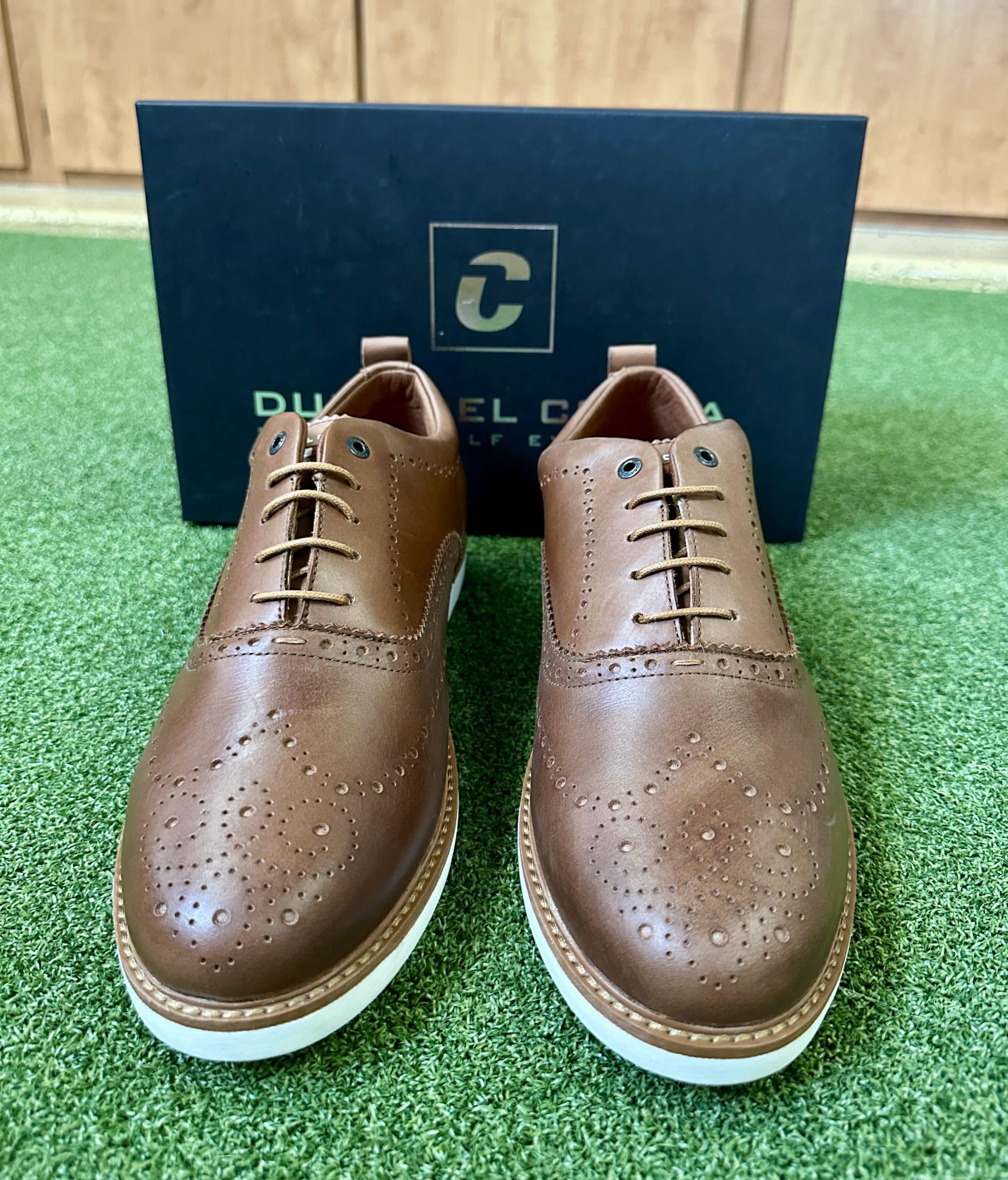 Brown leather brogue shoes on green turf