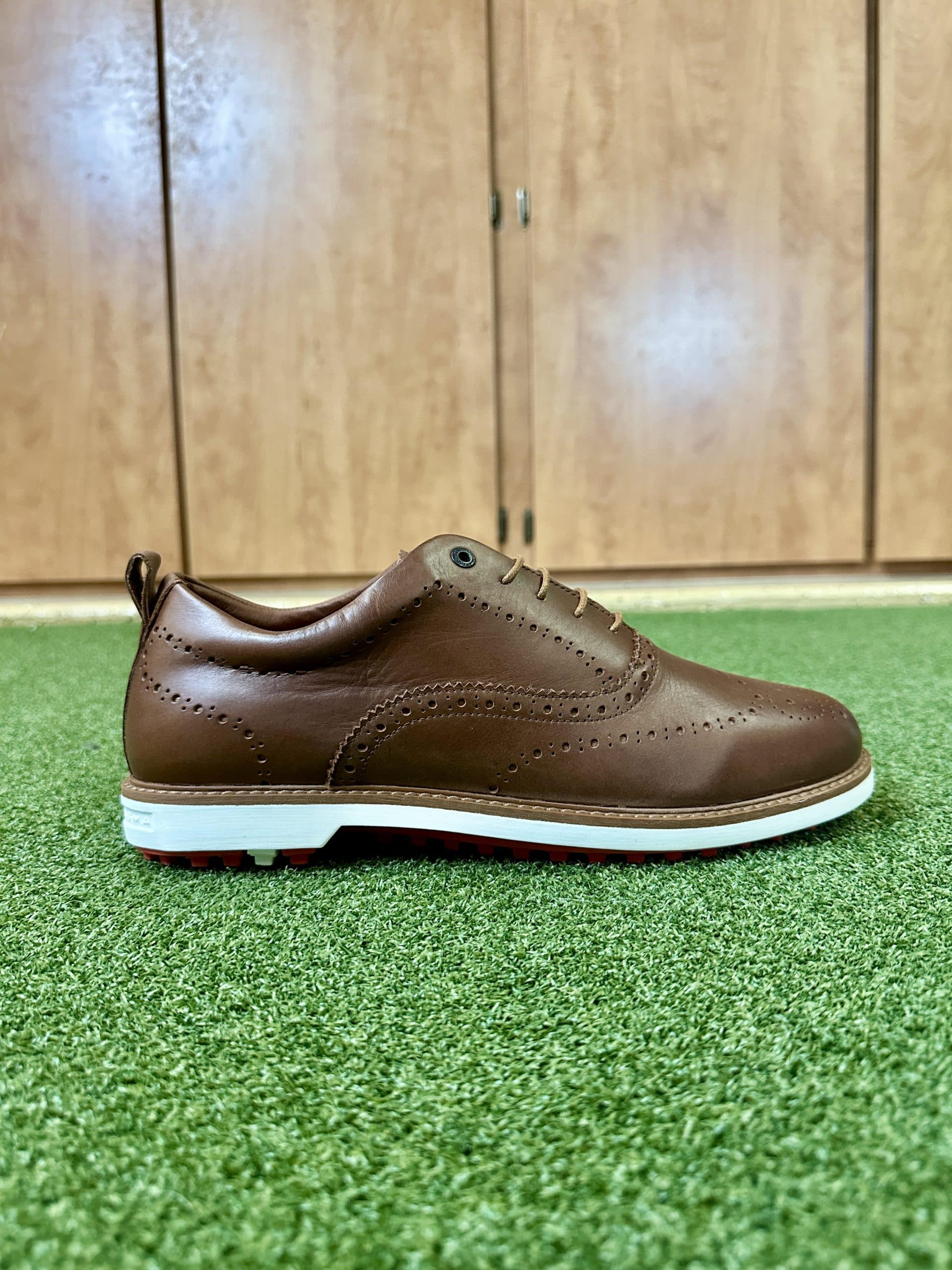 Brown leather golf shoe on green turf
