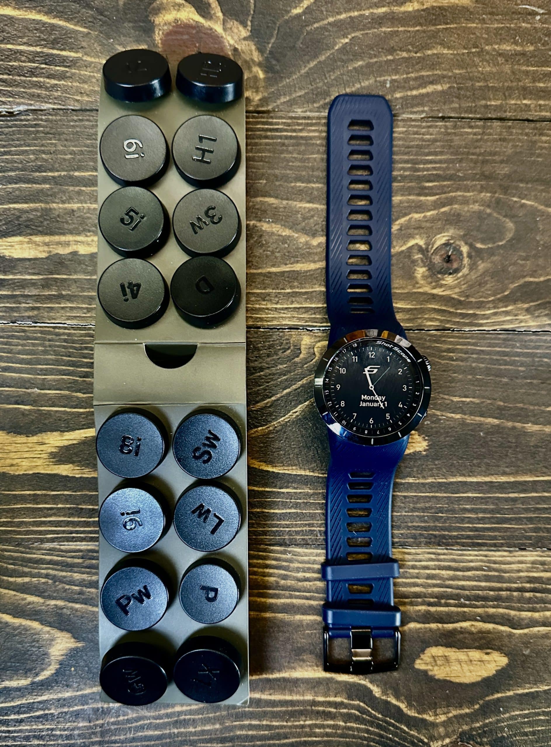 Golf club iron labels and smartwatch on wood table