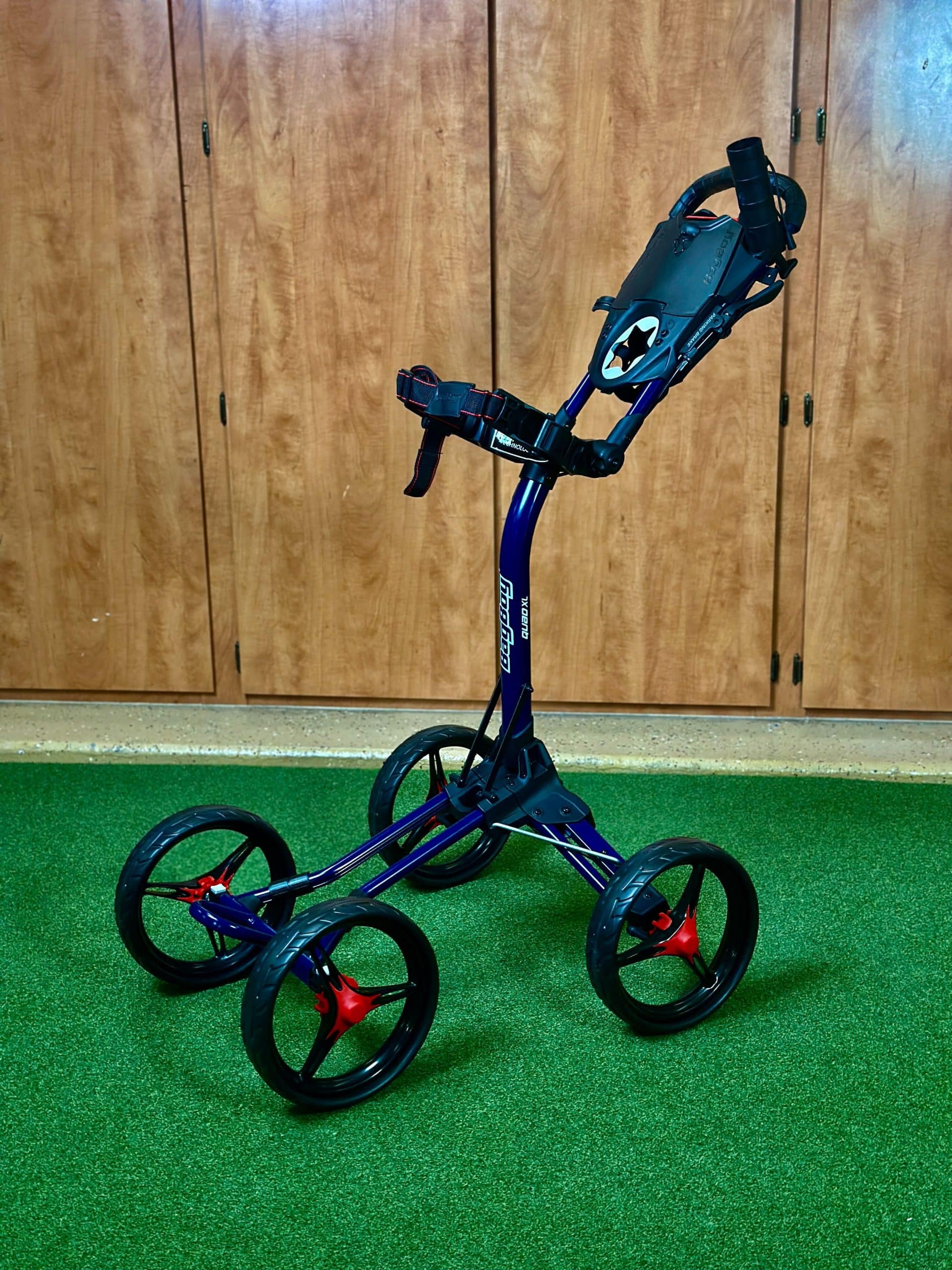 Four-wheel golf push cart on green turf
