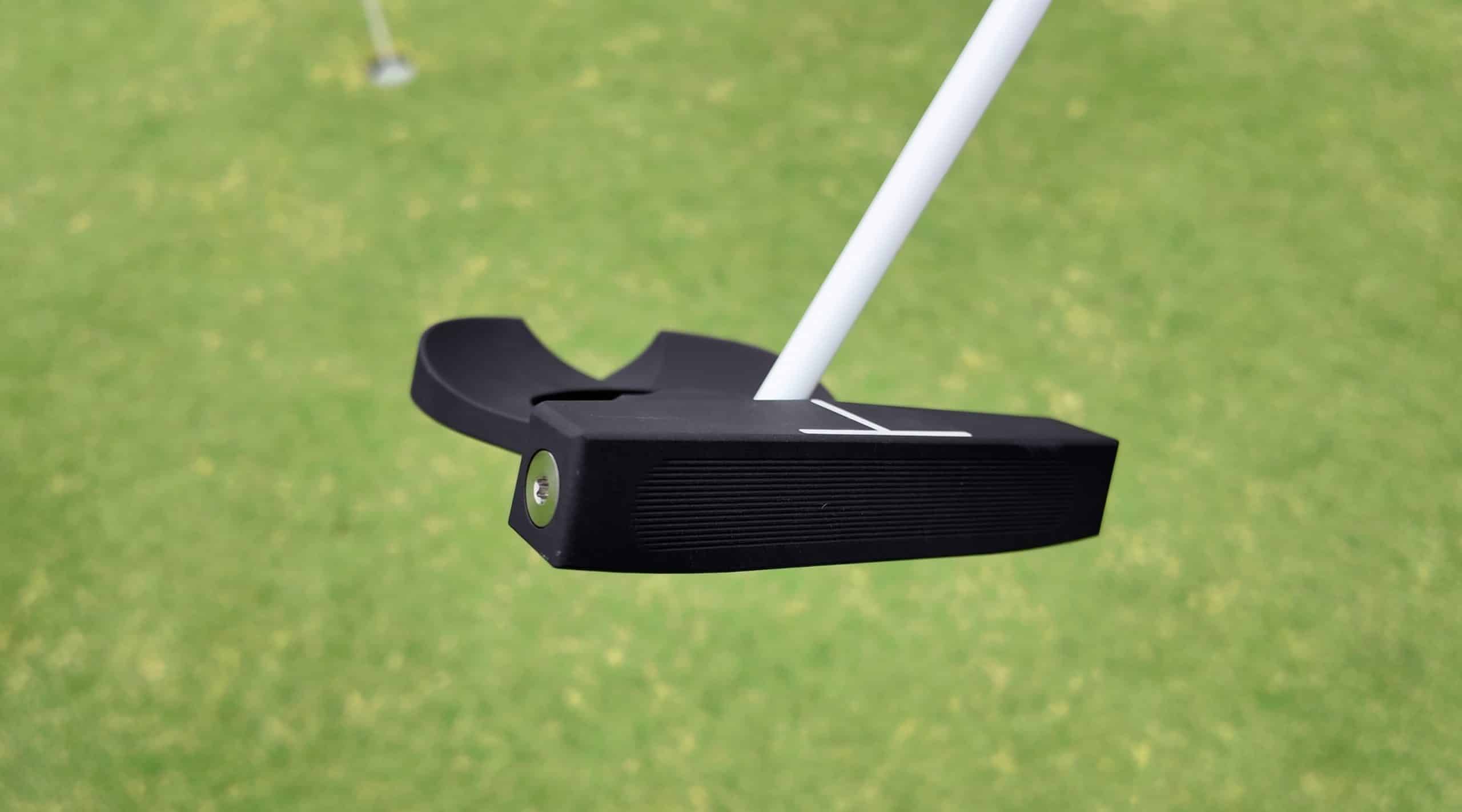 Black golf putter on green grass
