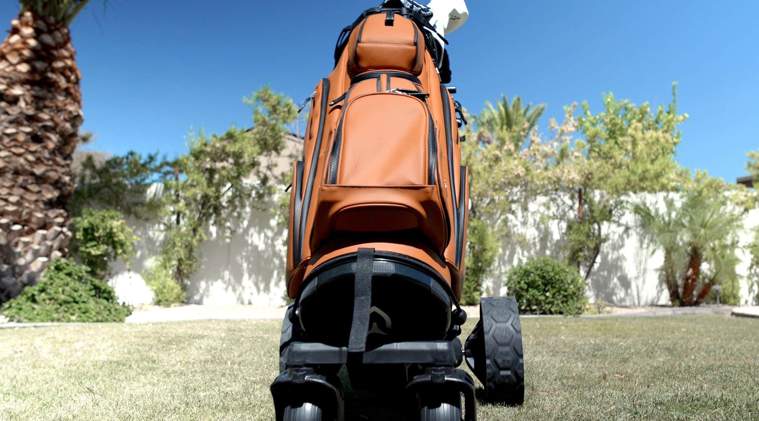 Brown golf bag on wheeled cart outdoors
