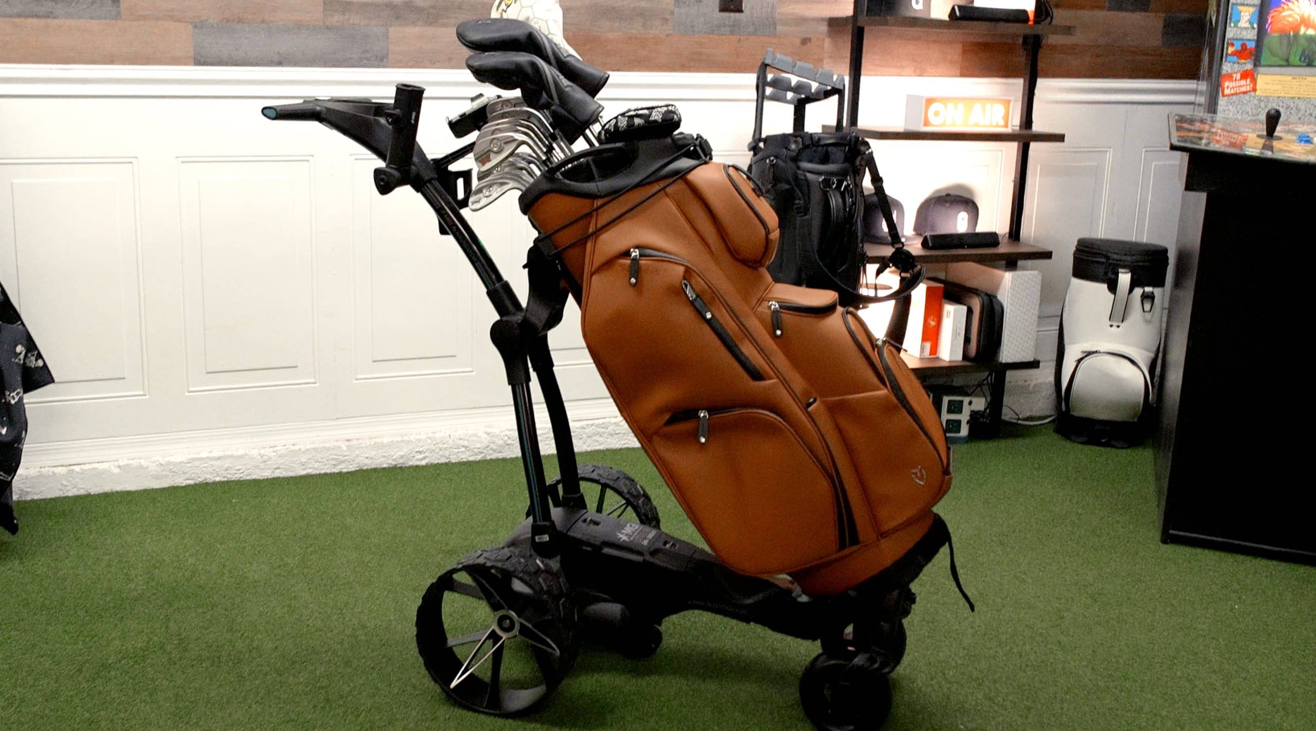Brown golf bag on electric push cart indoors