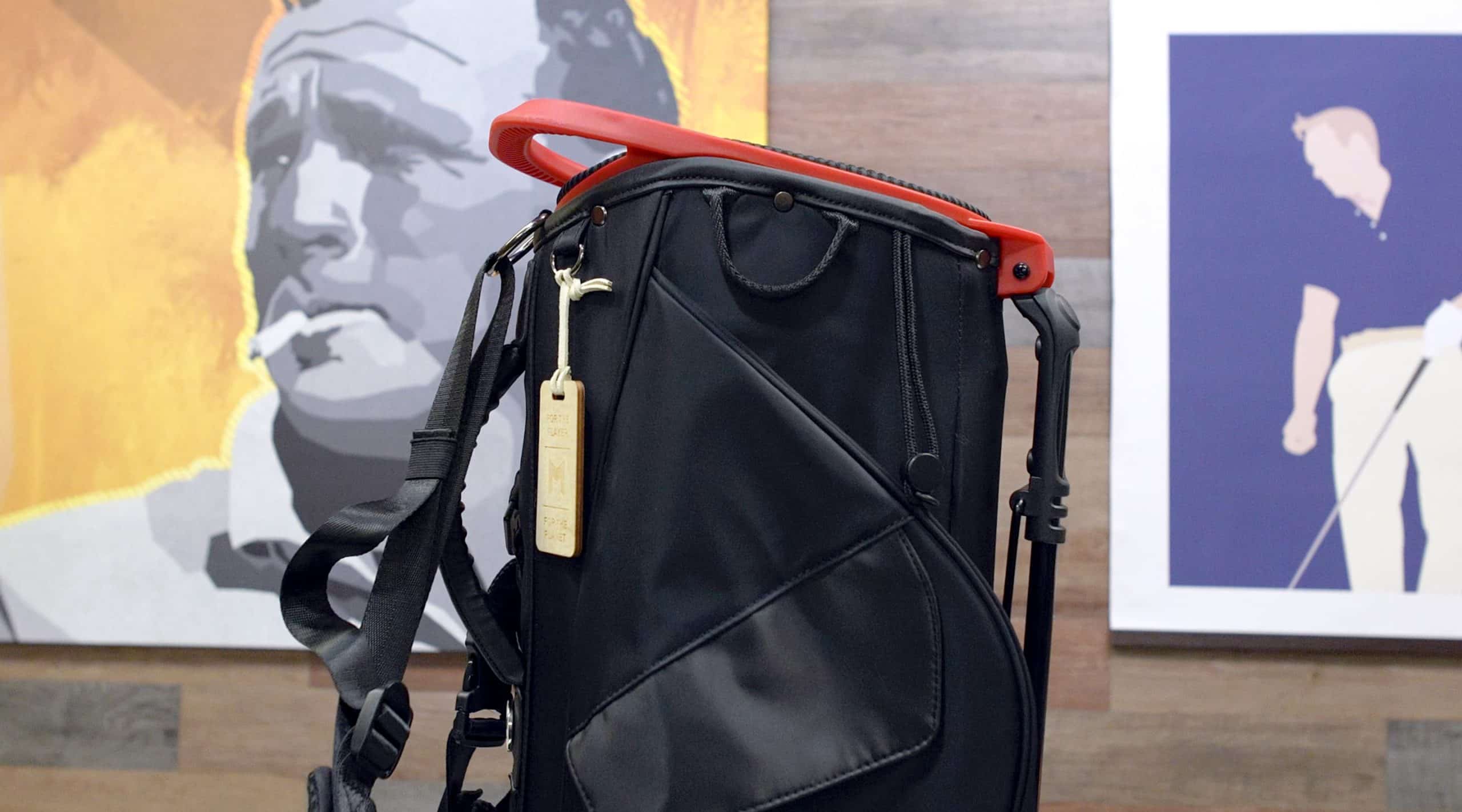Black golf bag with red handle indoors