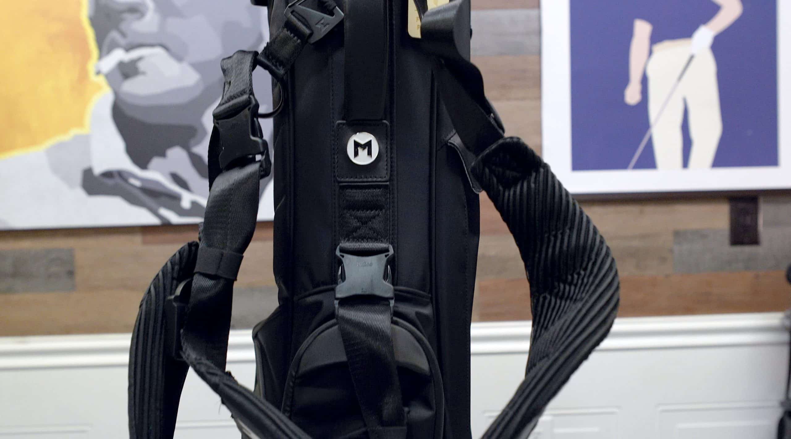 Black golf bag with shoulder straps indoors