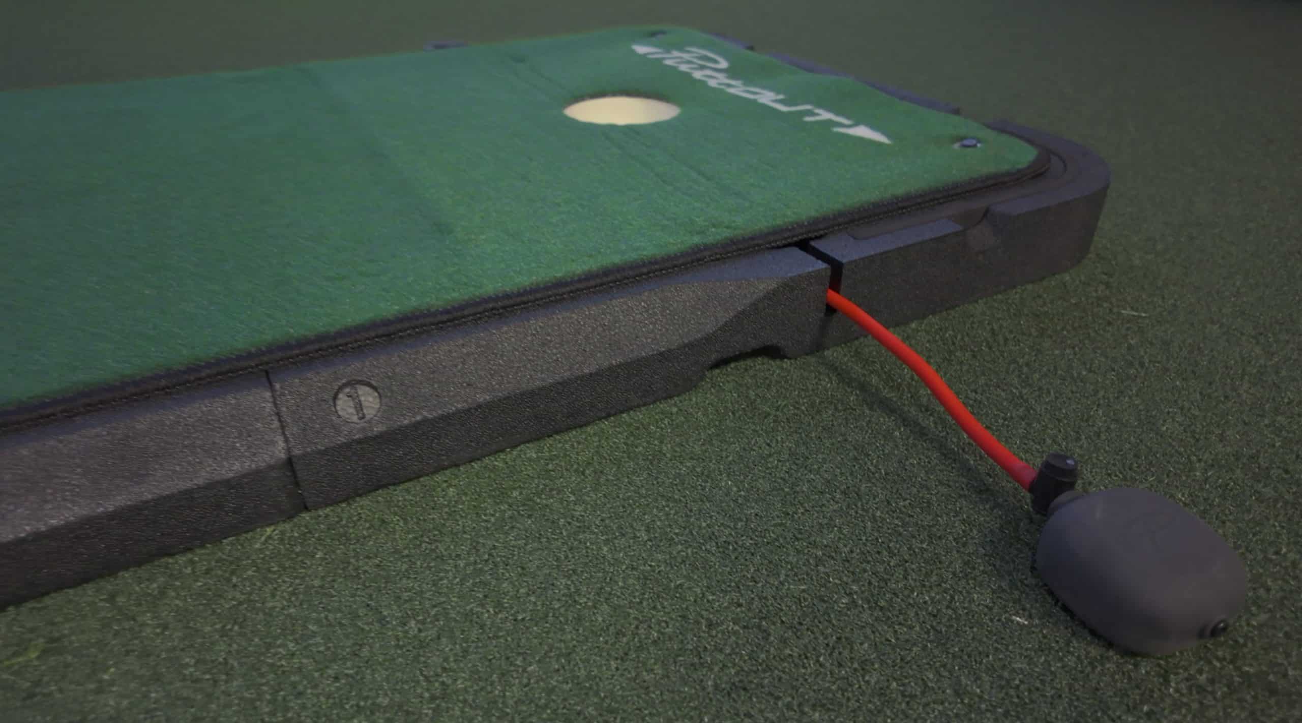 Golf putting mat with red cable connection