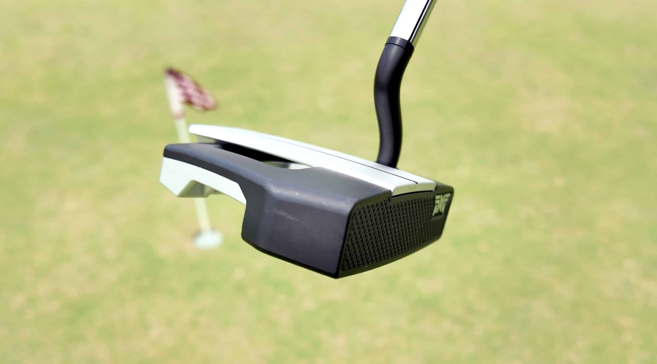 Modern golf putter on green field
