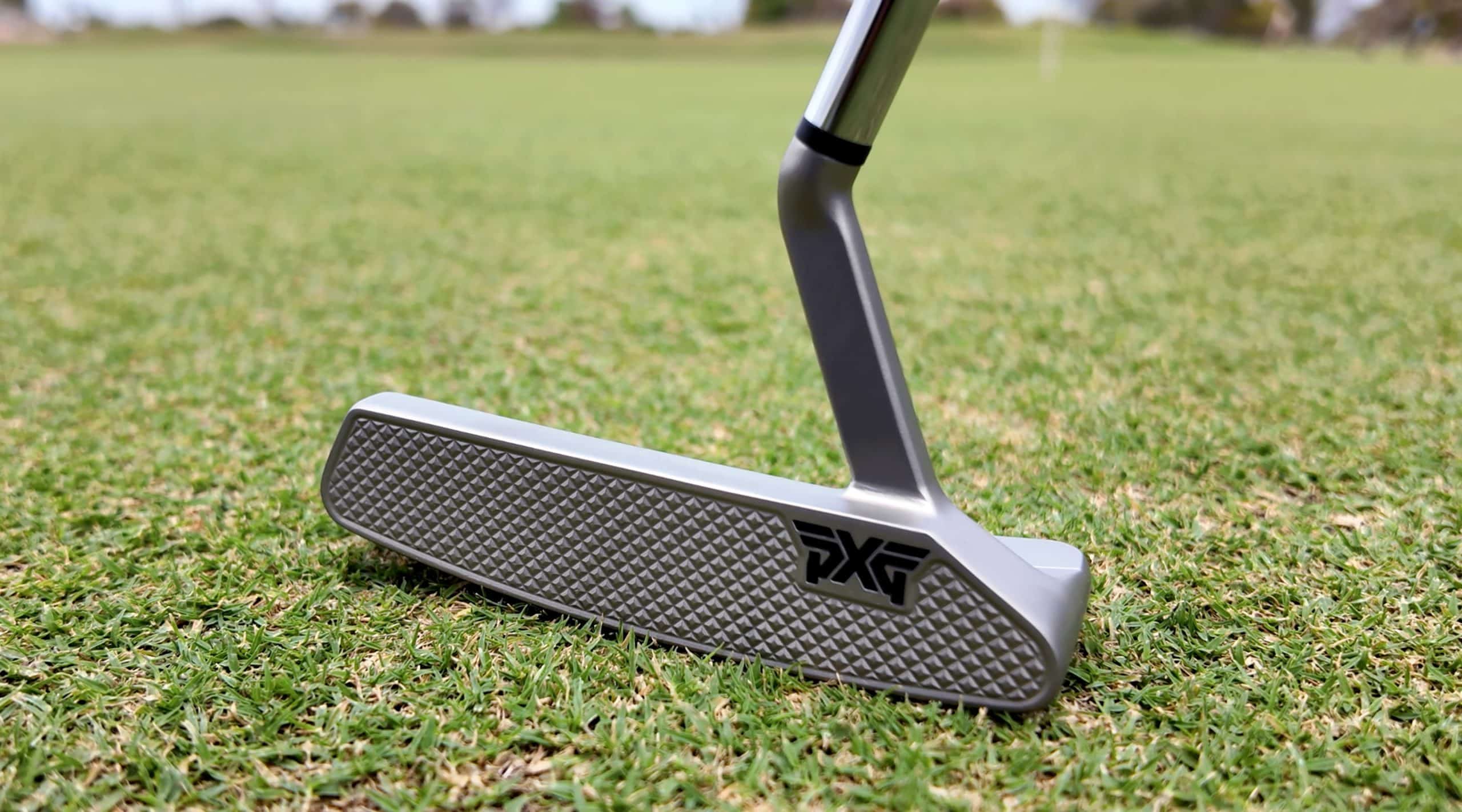 Silver golf putter on green grass