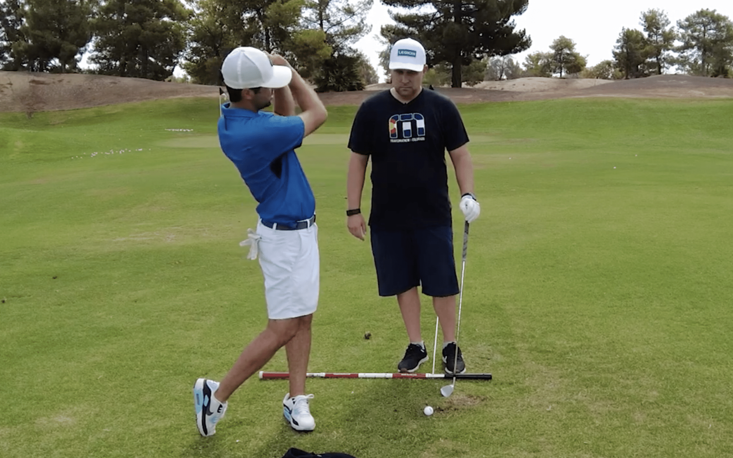 Golf instructor teaching student on grassy course
