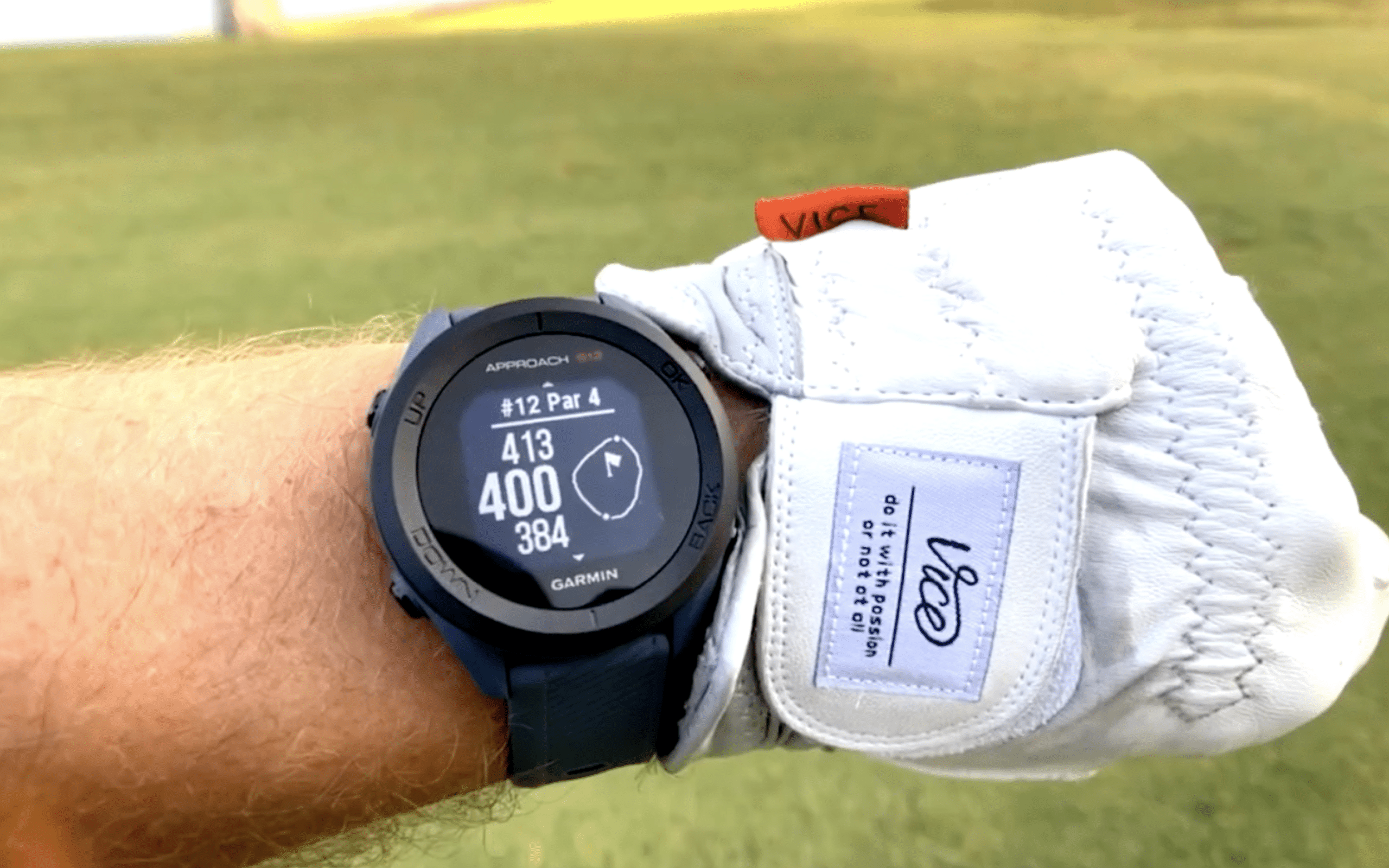 Golfer wearing Garmin watch showing course distance