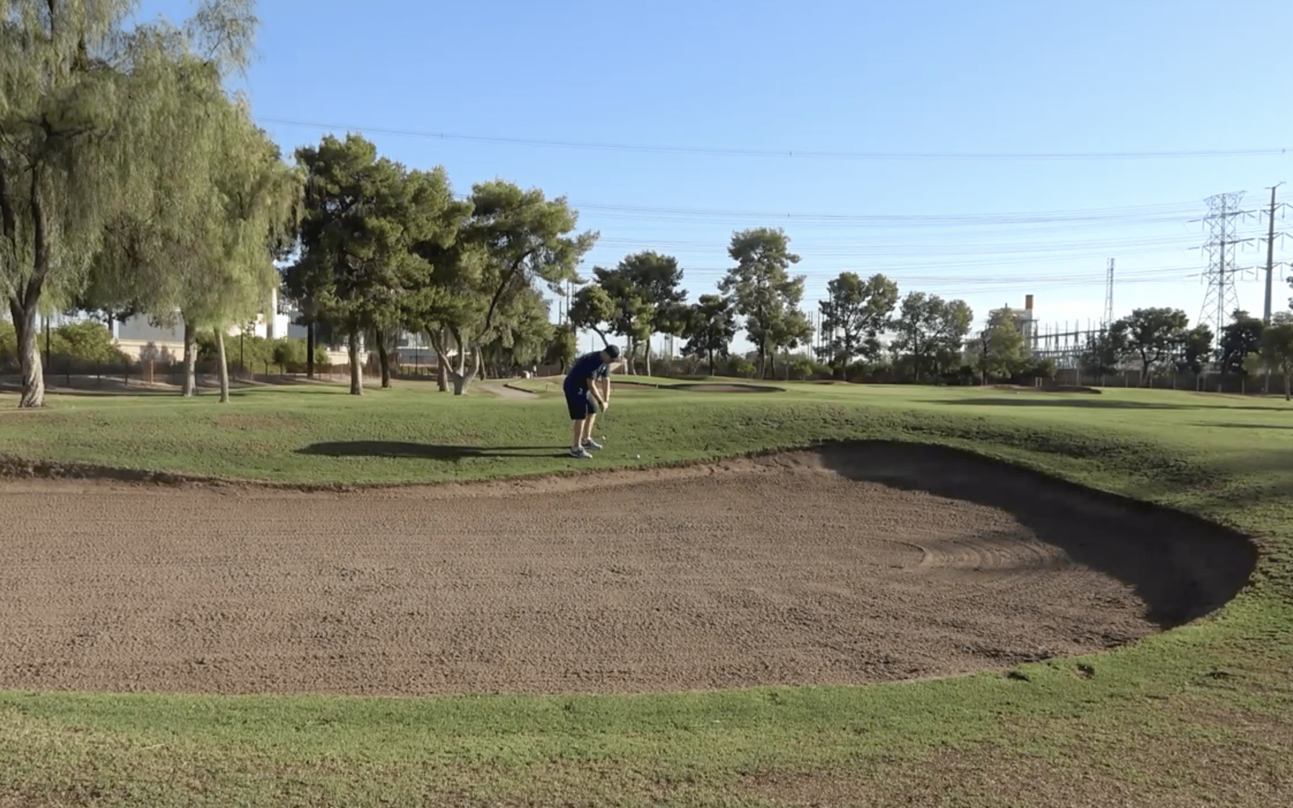 Golfer preparing to hit near bunker on course