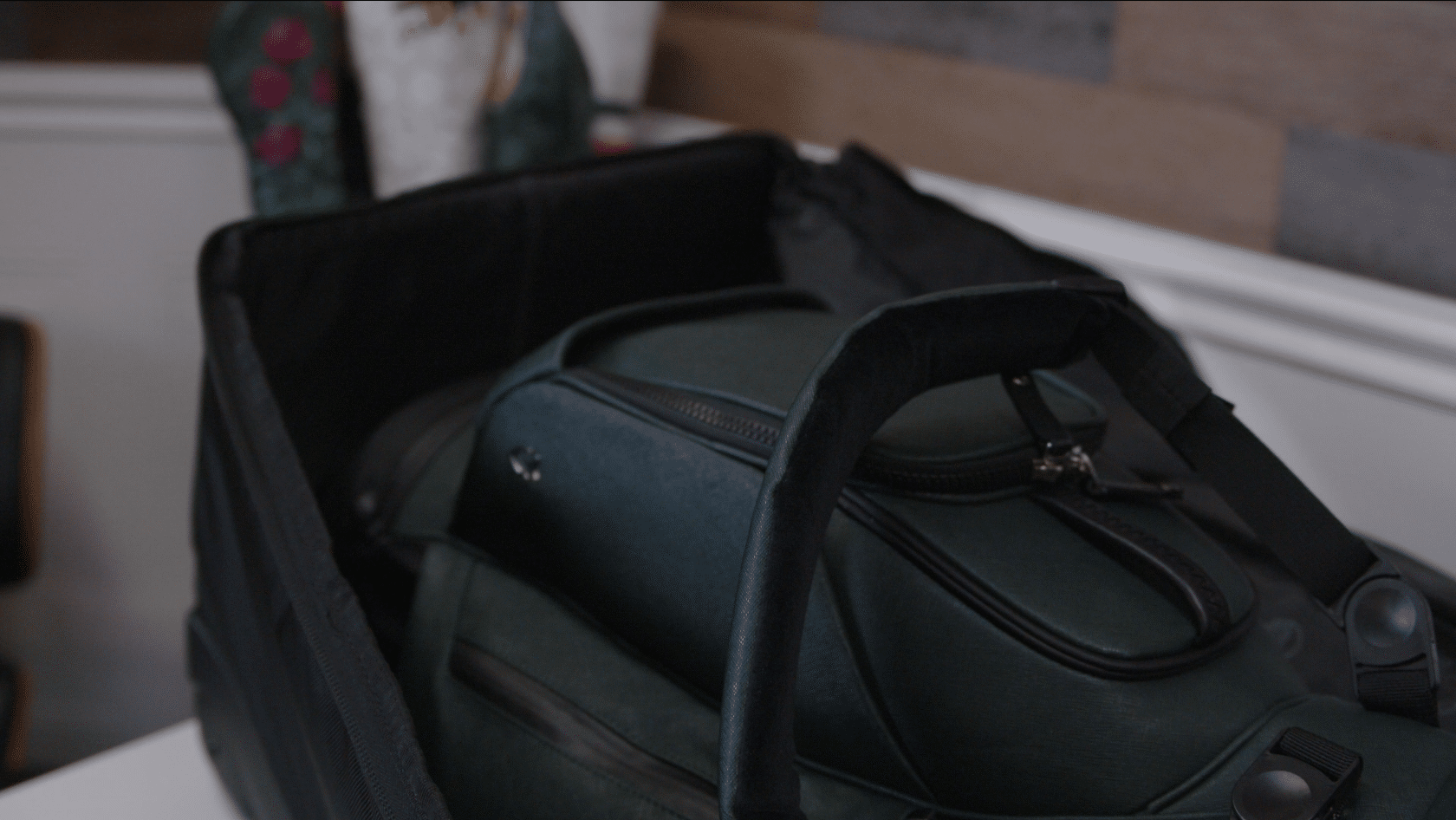 Green travel bag packed inside open suitcase