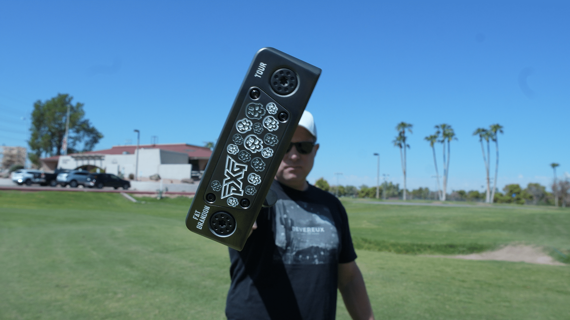 Golfer holding PXG putter on sunny golf course