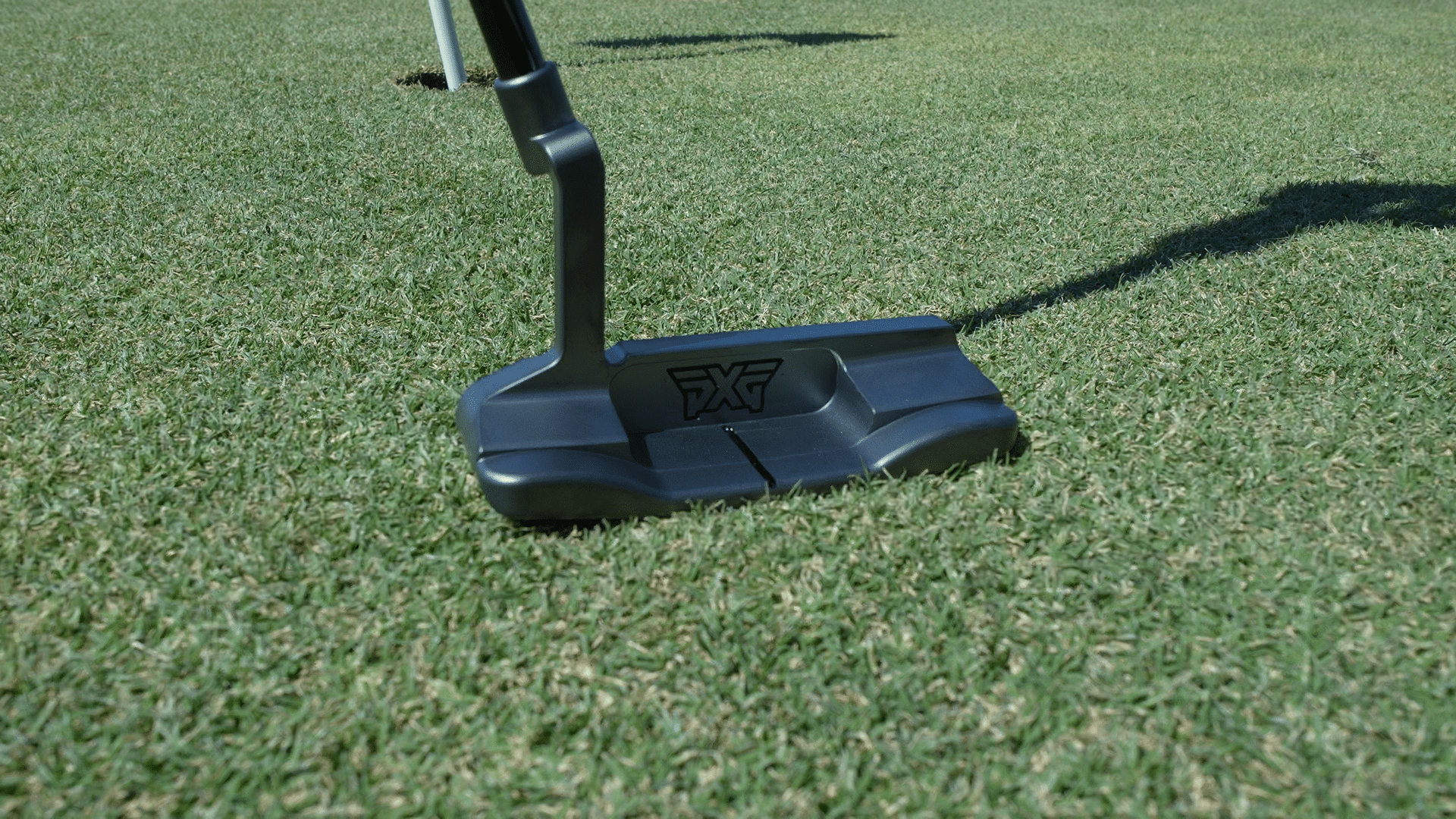 Golf putter on green near hole
