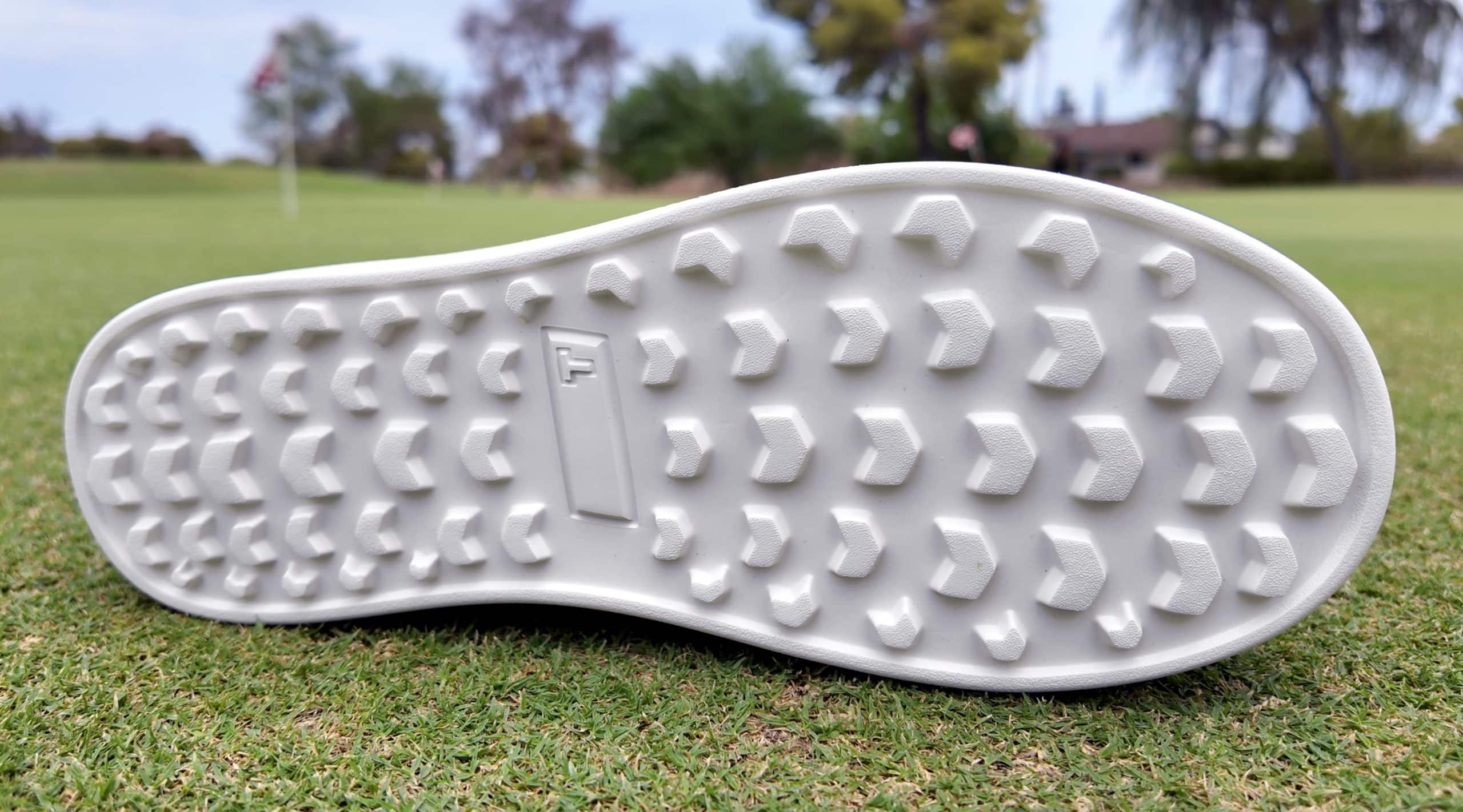 White golf shoe sole on green grass