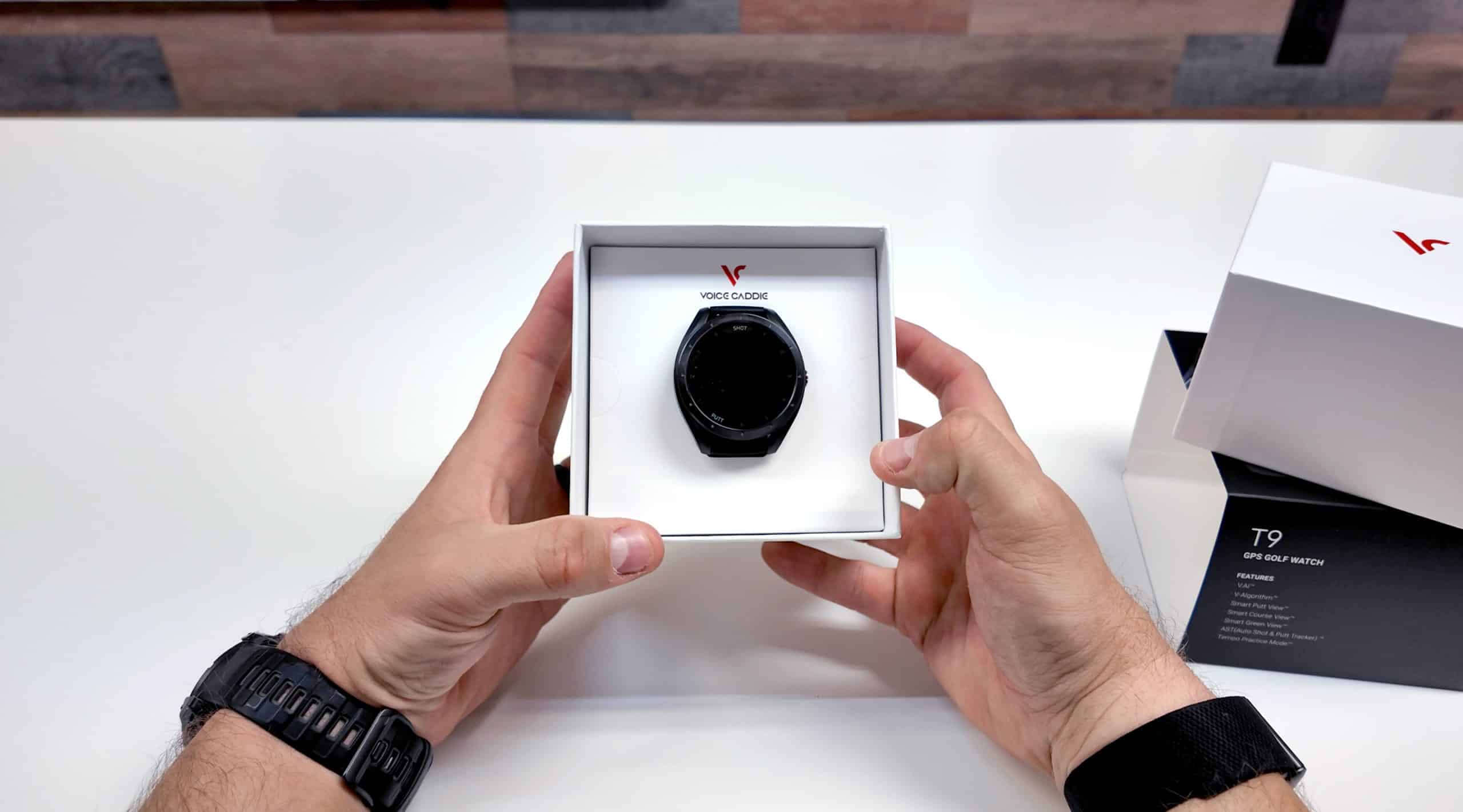 Person unboxing a black GPS golf watch