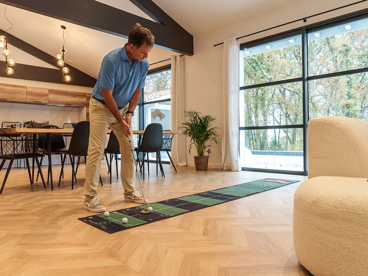 Man practicing indoor golf putting at home