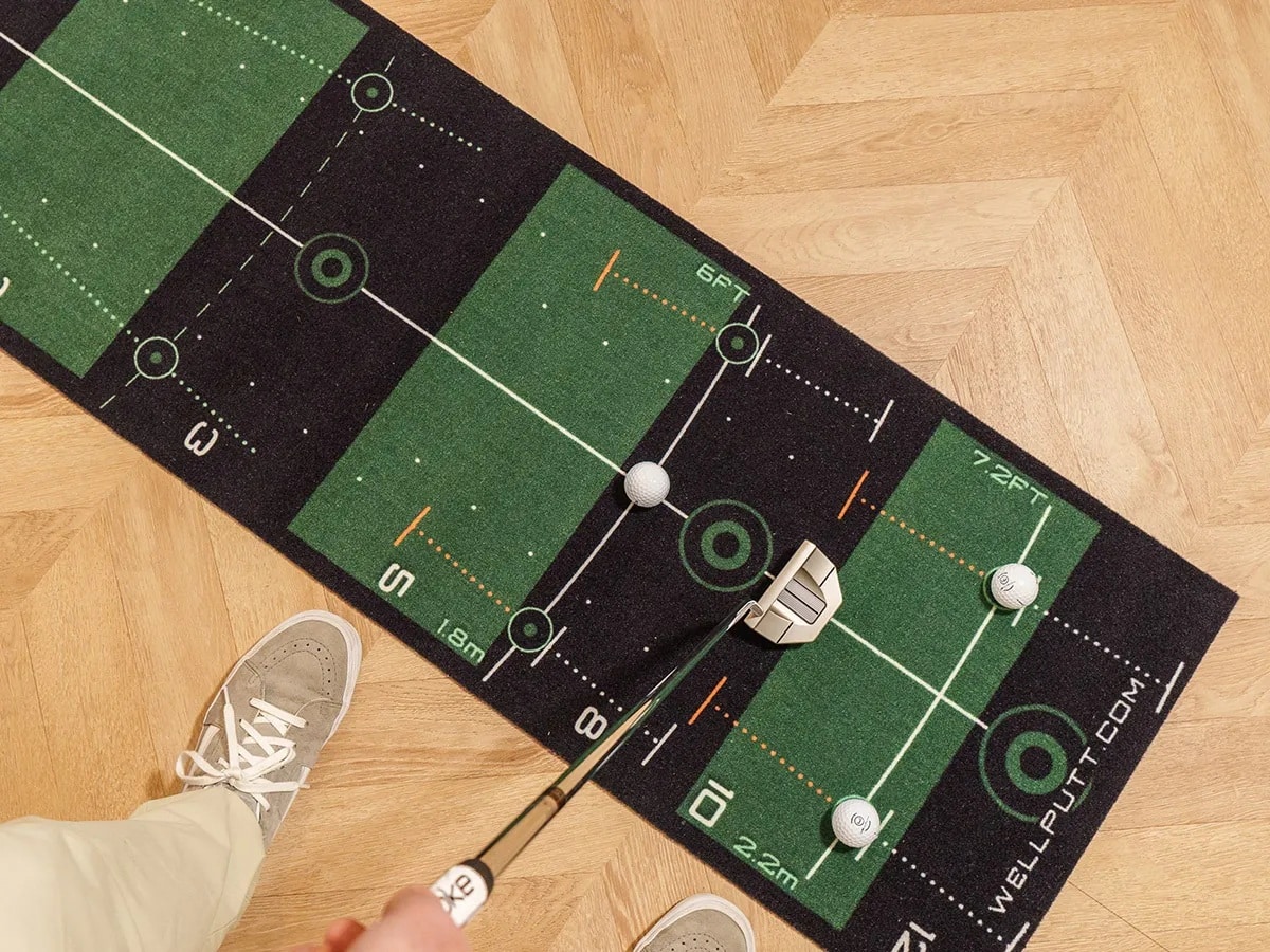 Person practicing putting on indoor golf mat