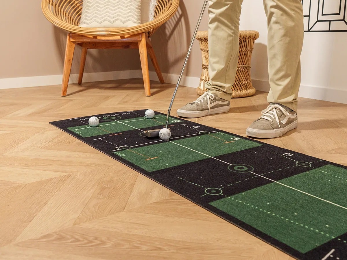 Person practicing putting on indoor golf mat