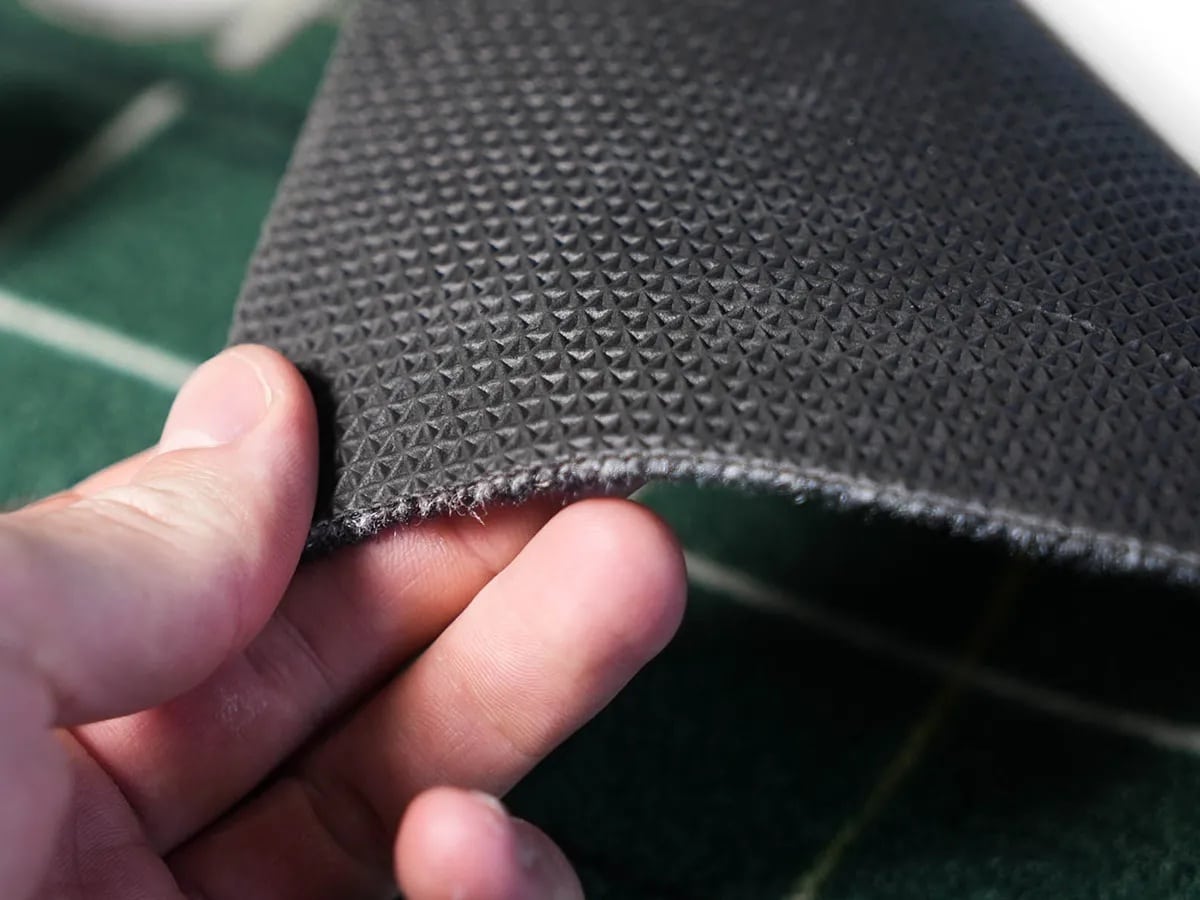 Hand holding textured black rubber mat