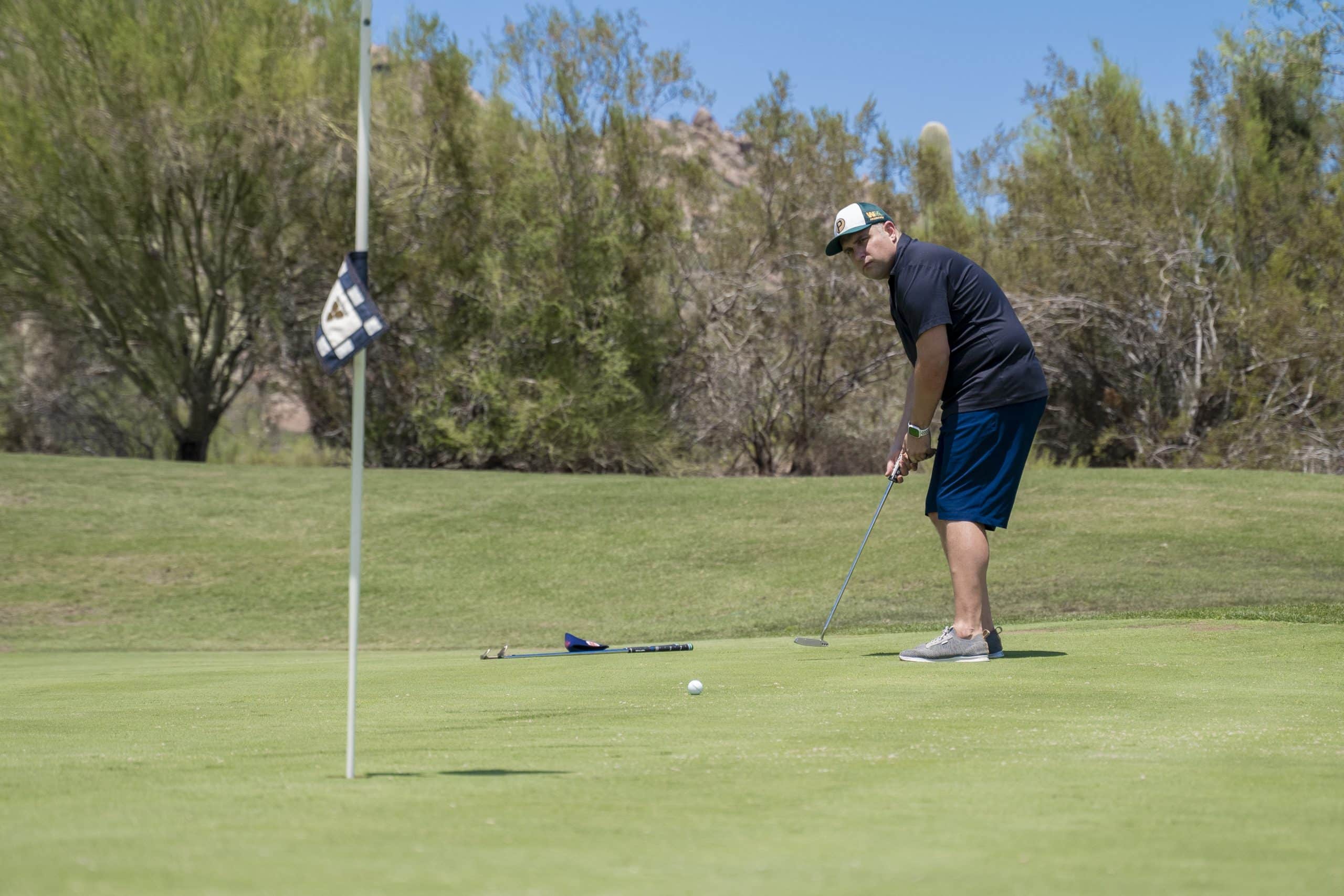 Golfer putting on sunny green course