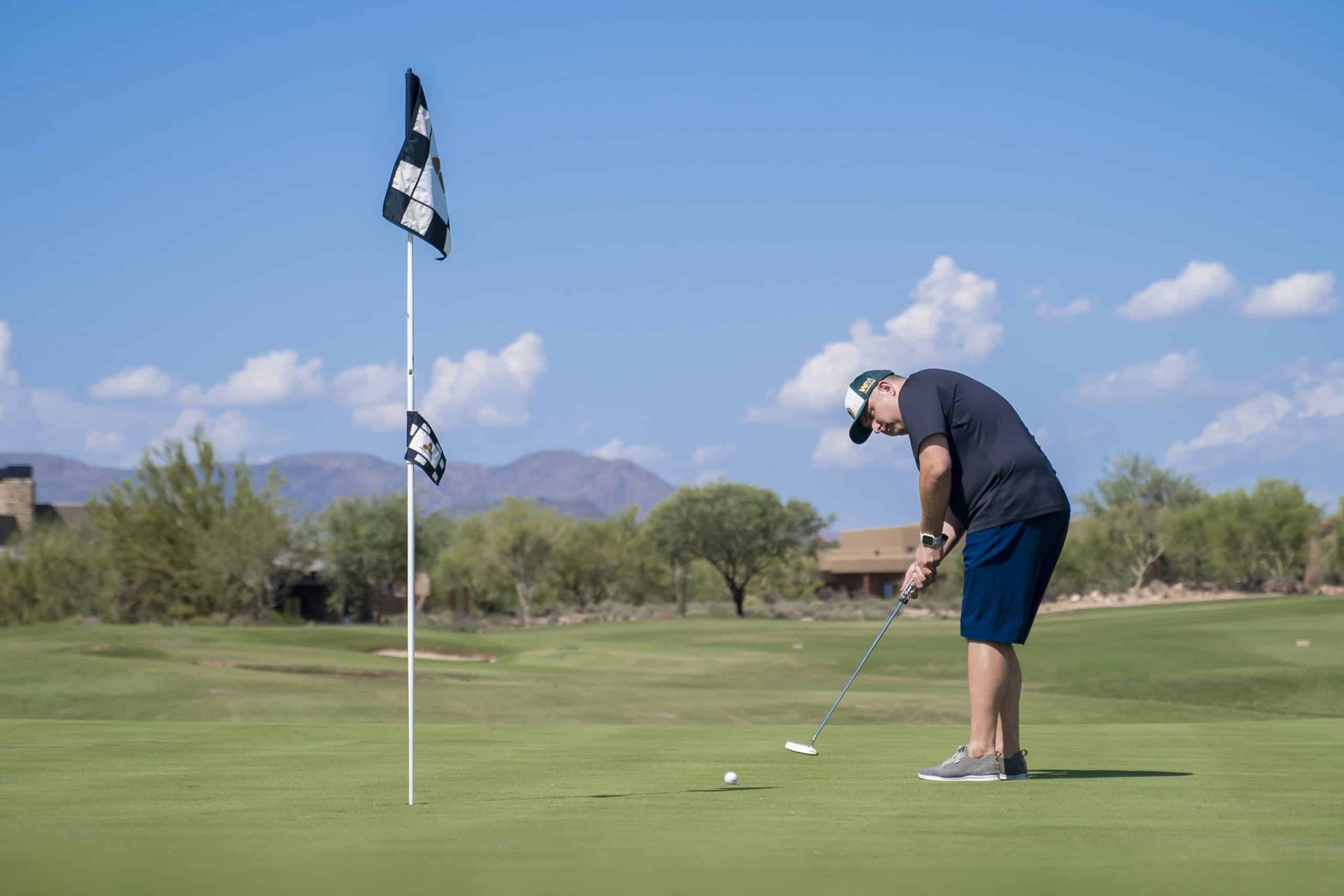 Golfer putting on sunny golf course
