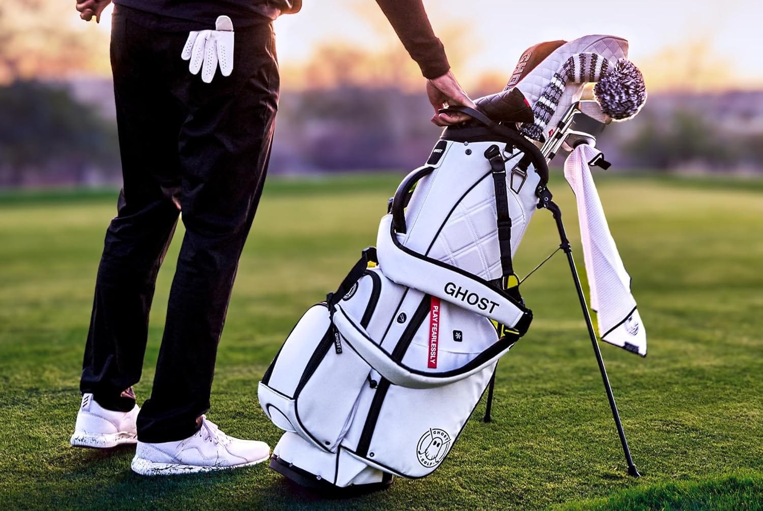 Golfer holding white golf bag on course