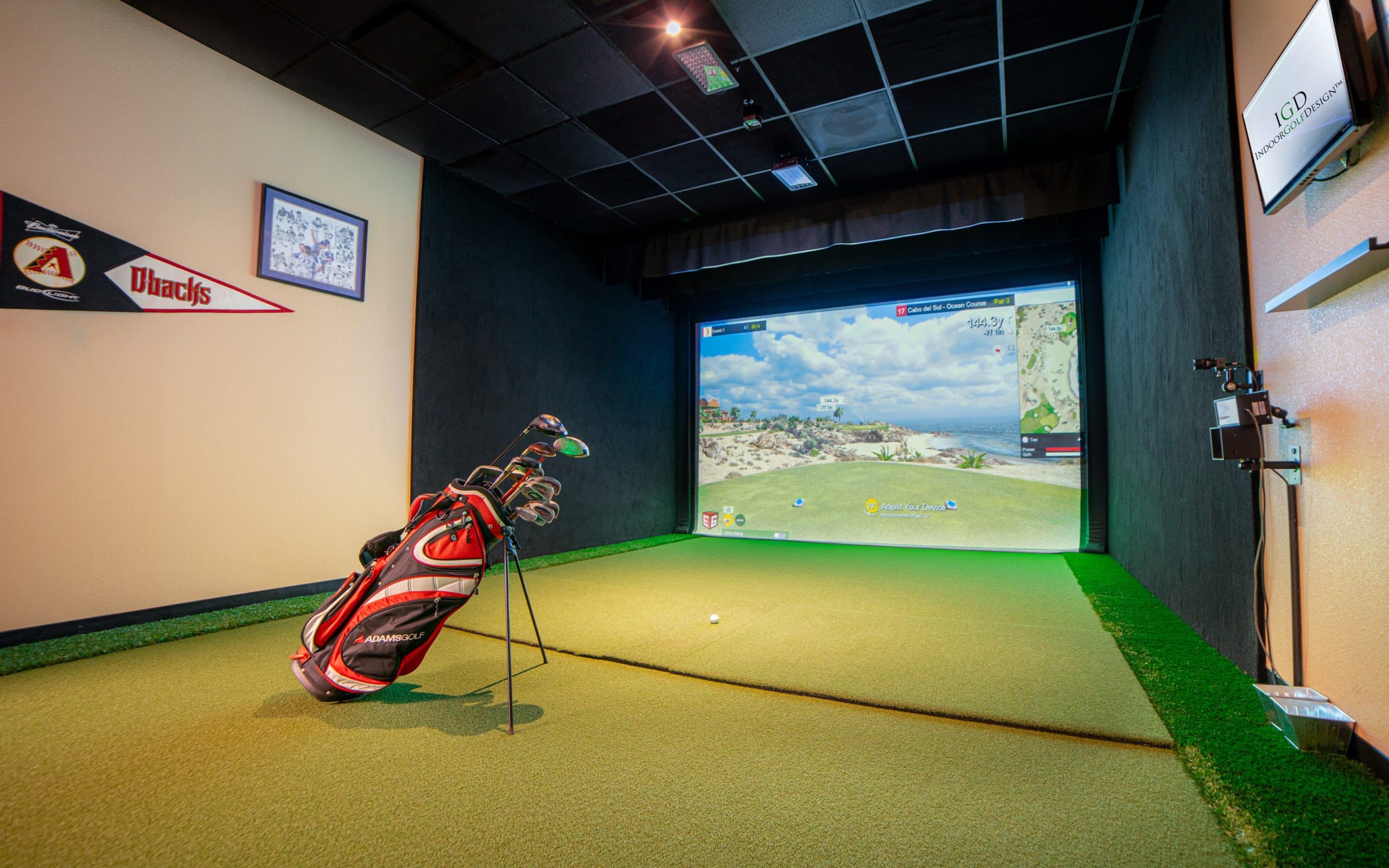 Indoor golf simulator with clubs and screen display