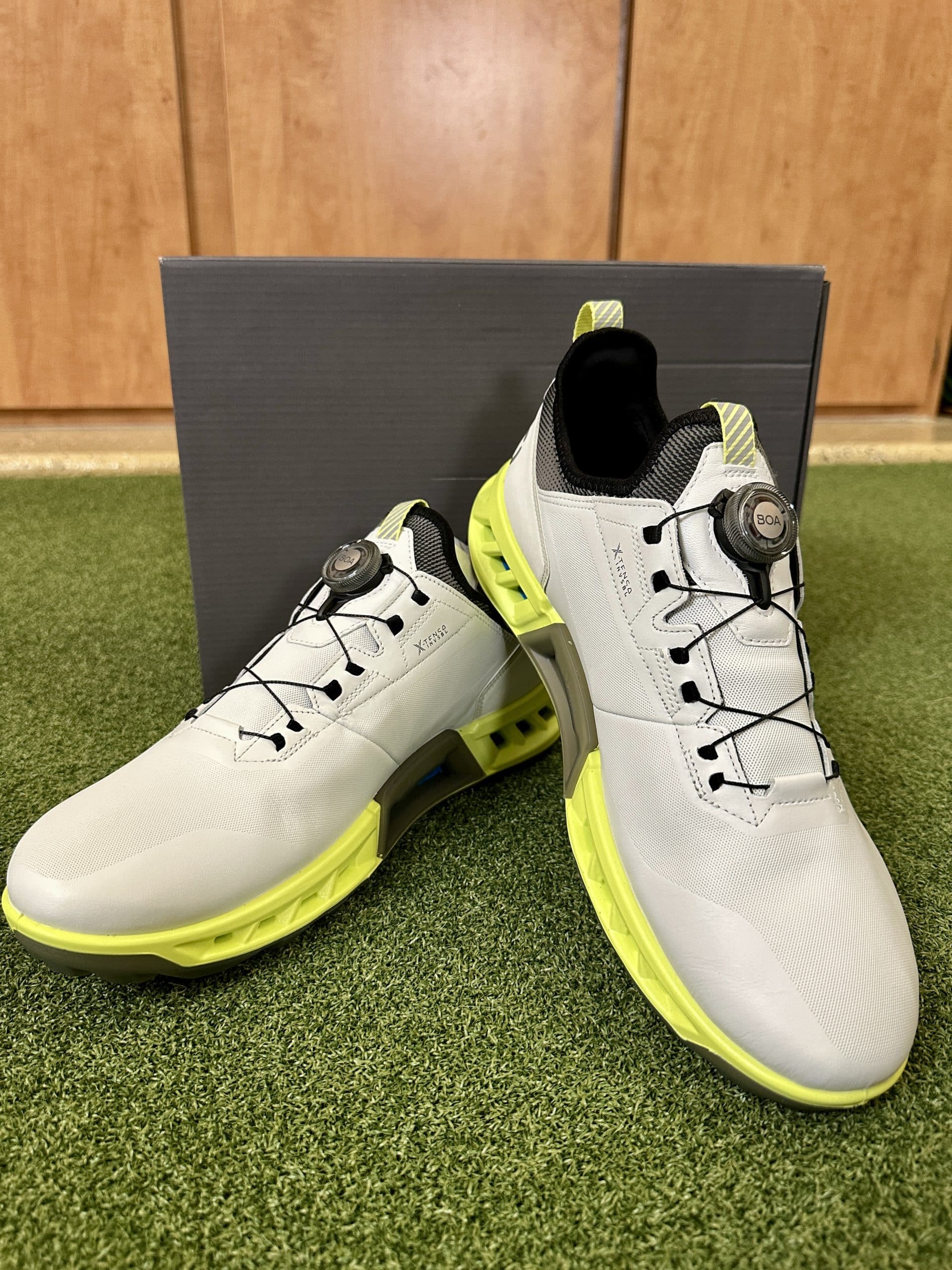 White and yellow athletic shoes on green turf