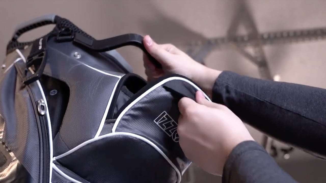 Person opening a gray golf bag pocket
