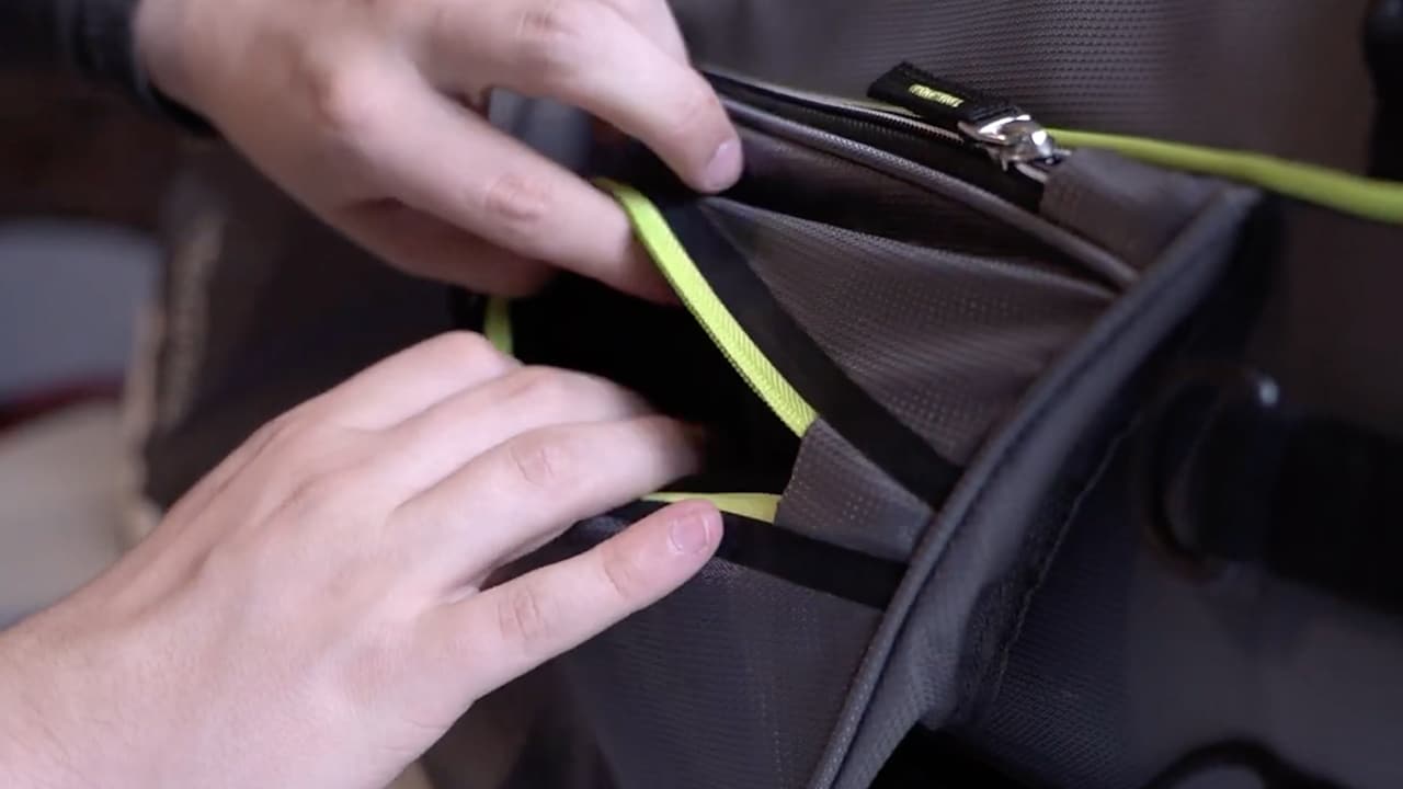 Hands opening a gray backpack pocket