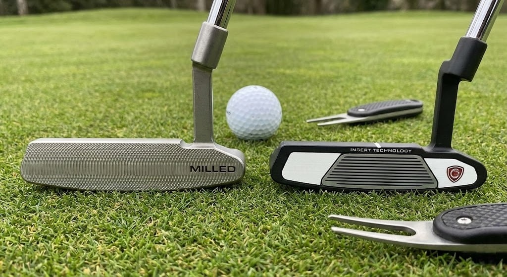 Two golf putters and a ball on green grass
