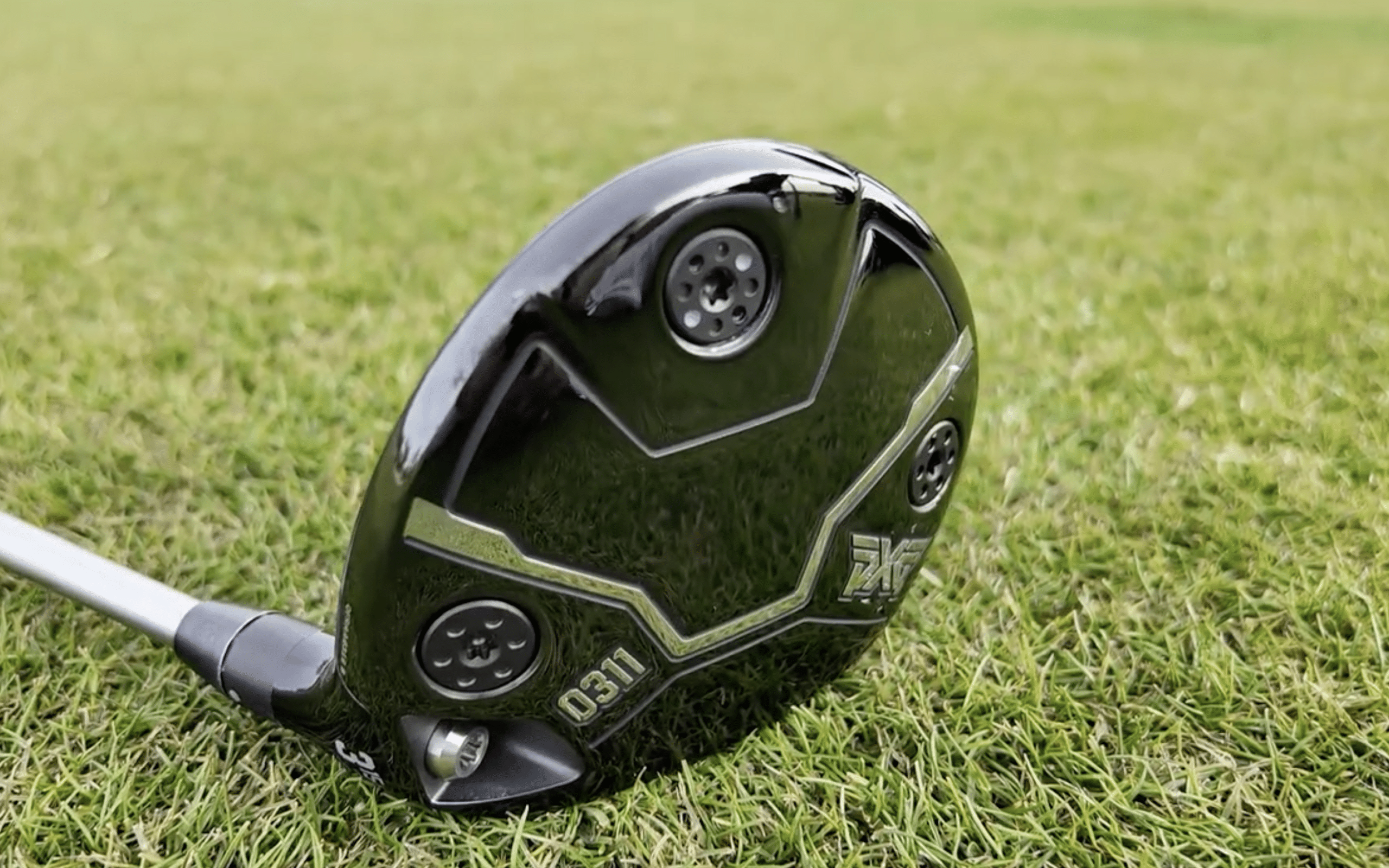 Black golf driver club resting on grass