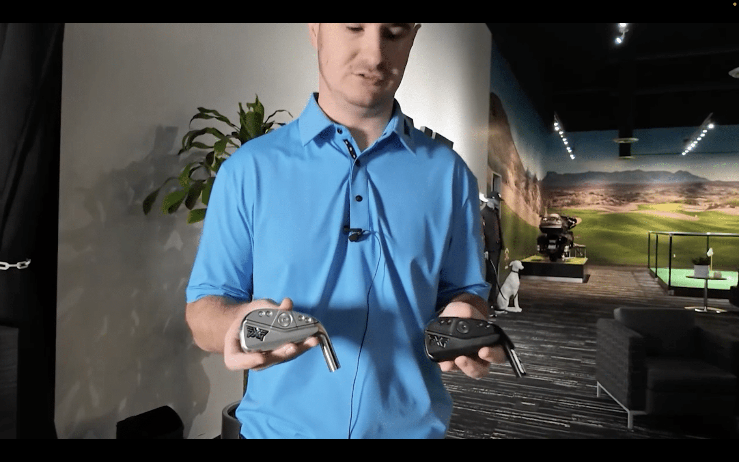 Man comparing two golf club heads indoors
