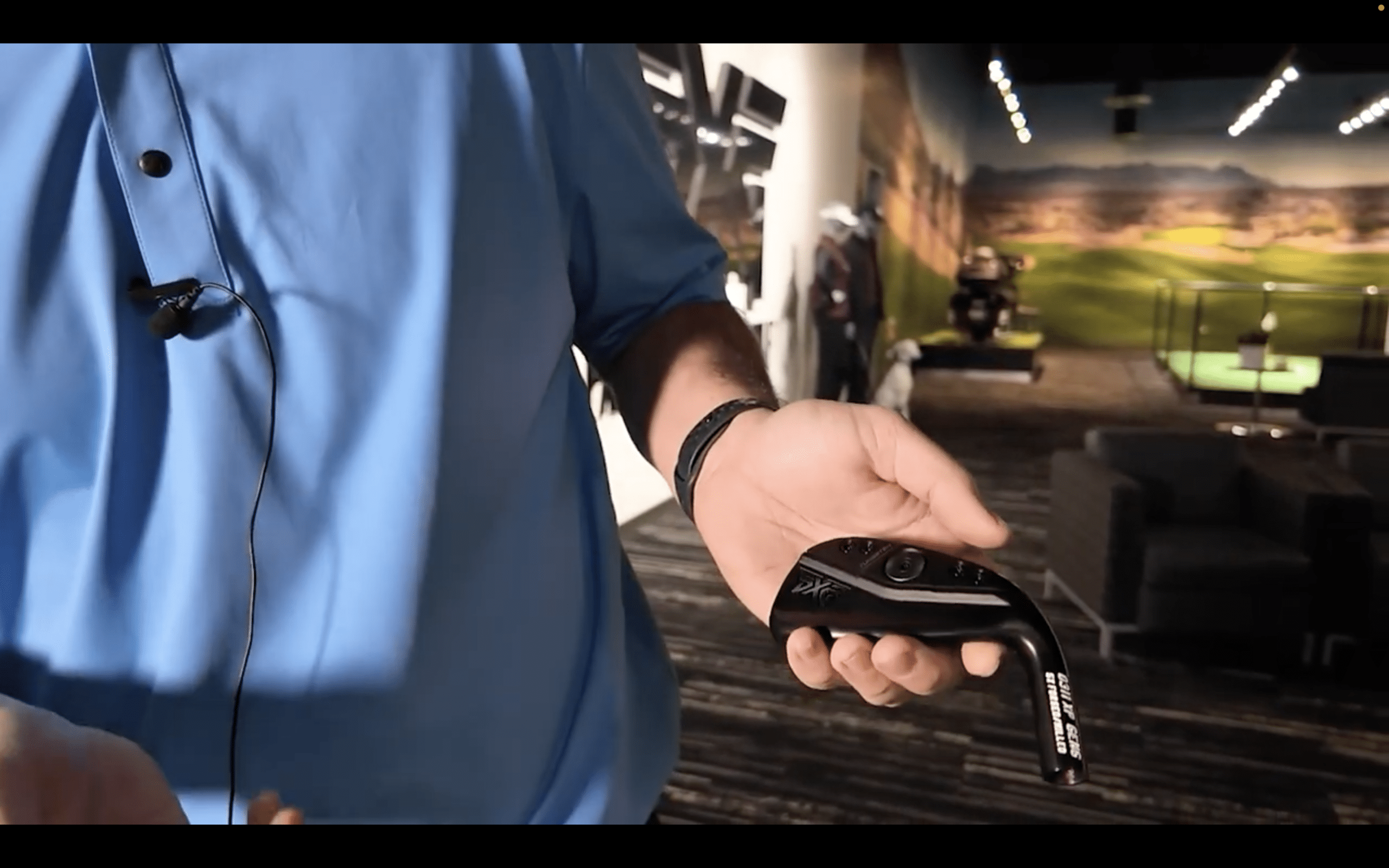 Person holding a black golf club head indoors