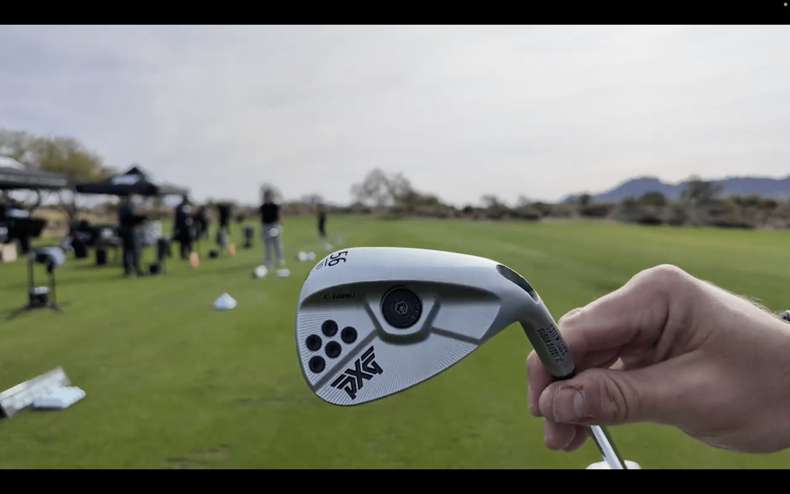 Golfer holding a silver golf wedge on course