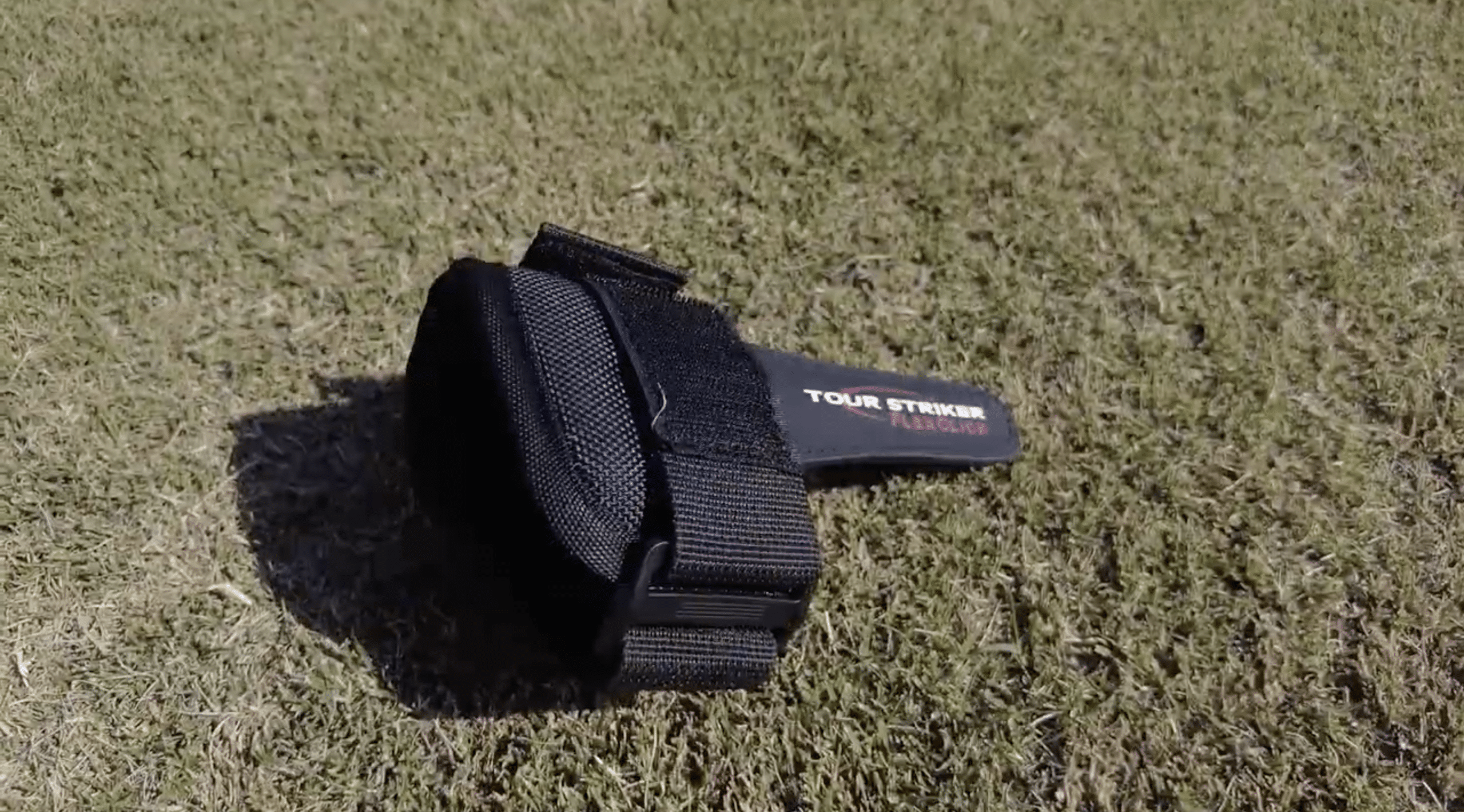 Black Tour Striker FlexClick golf training aid on grass