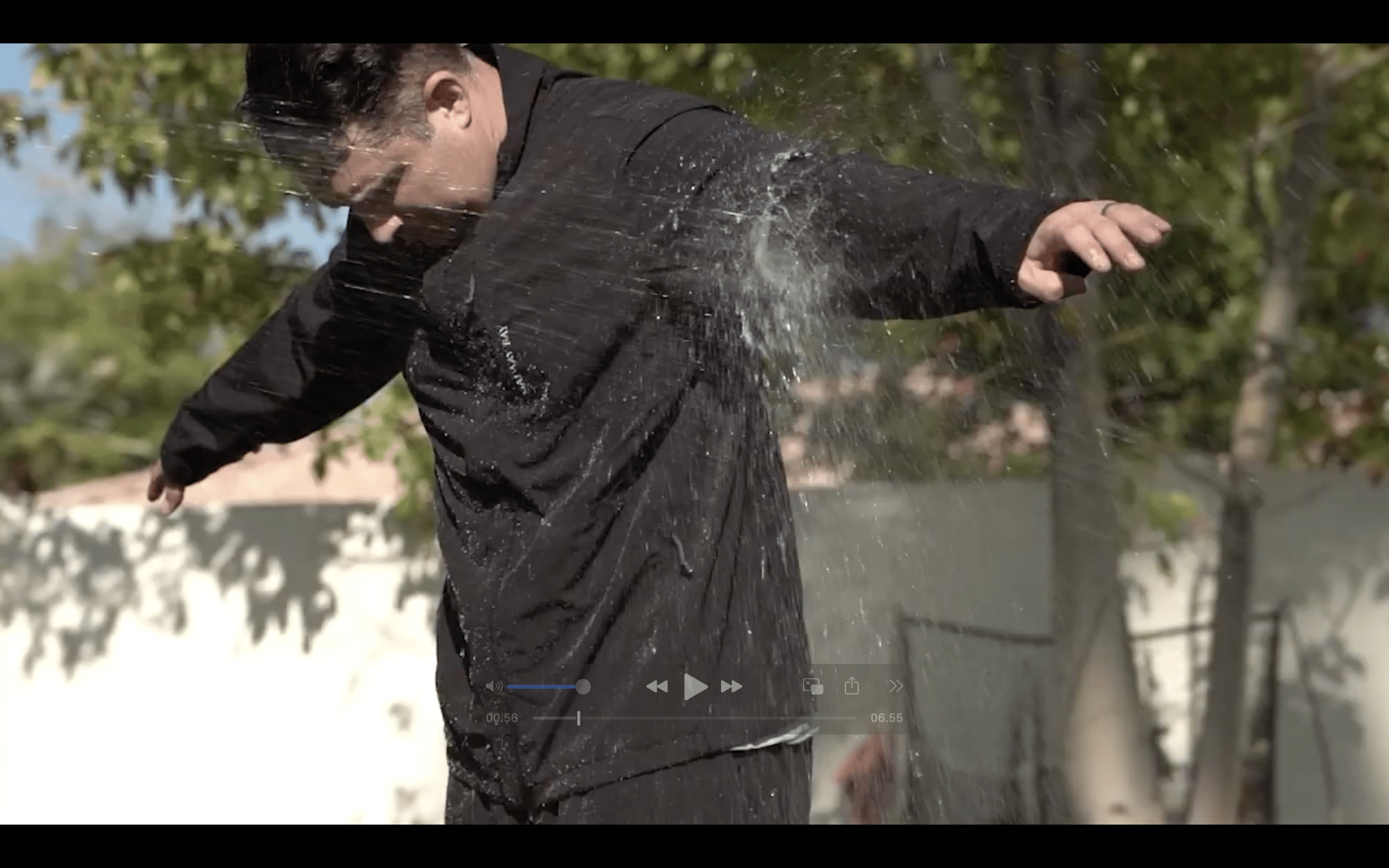 Person testing water-resistant black jacket outdoors