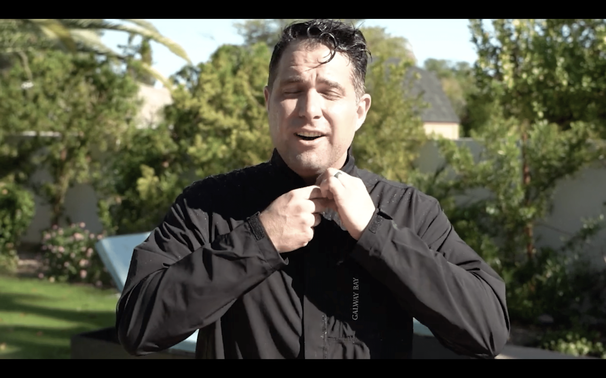 Man buttoning black jacket outdoors