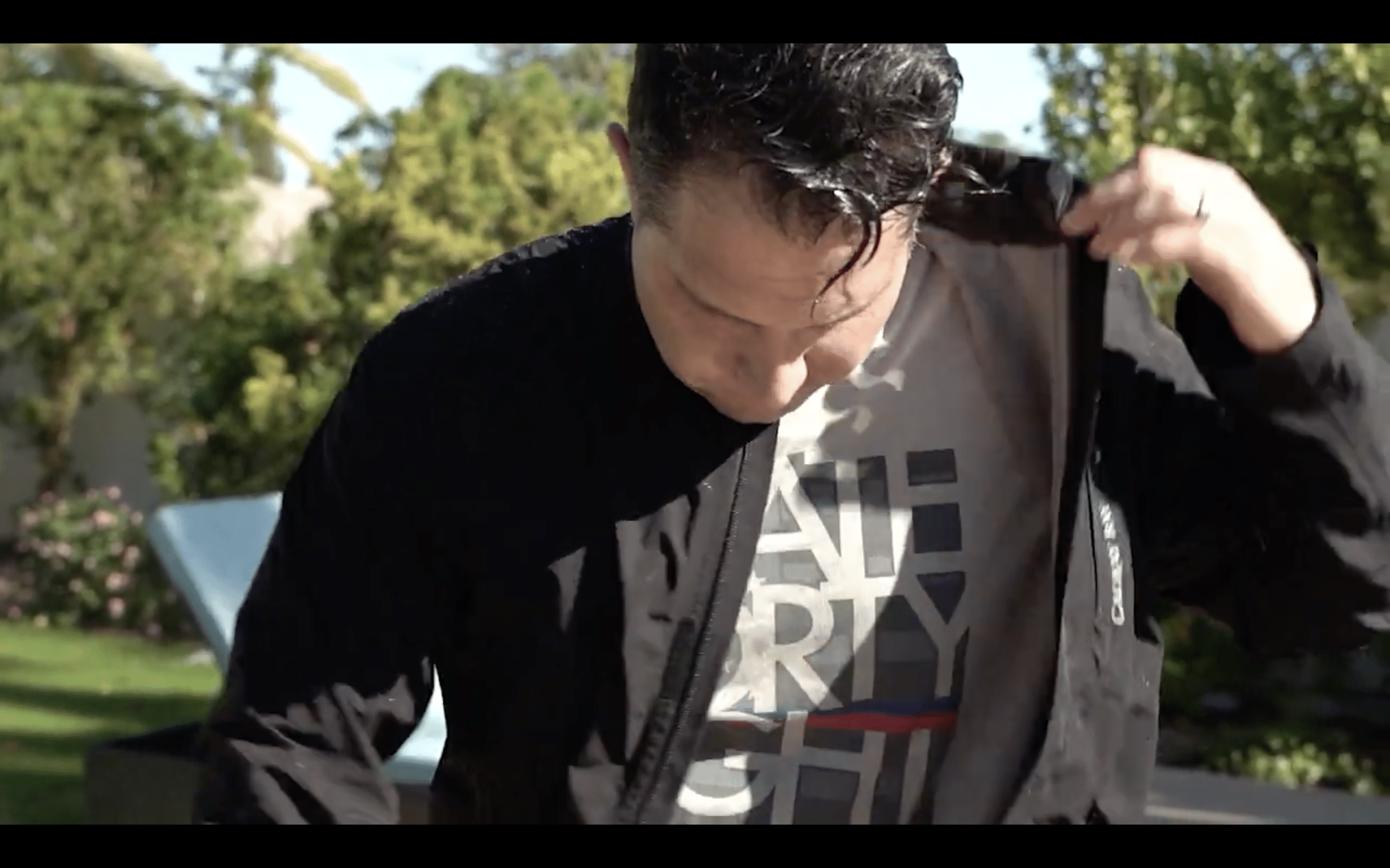 Man adjusting jacket outdoors in sunlight