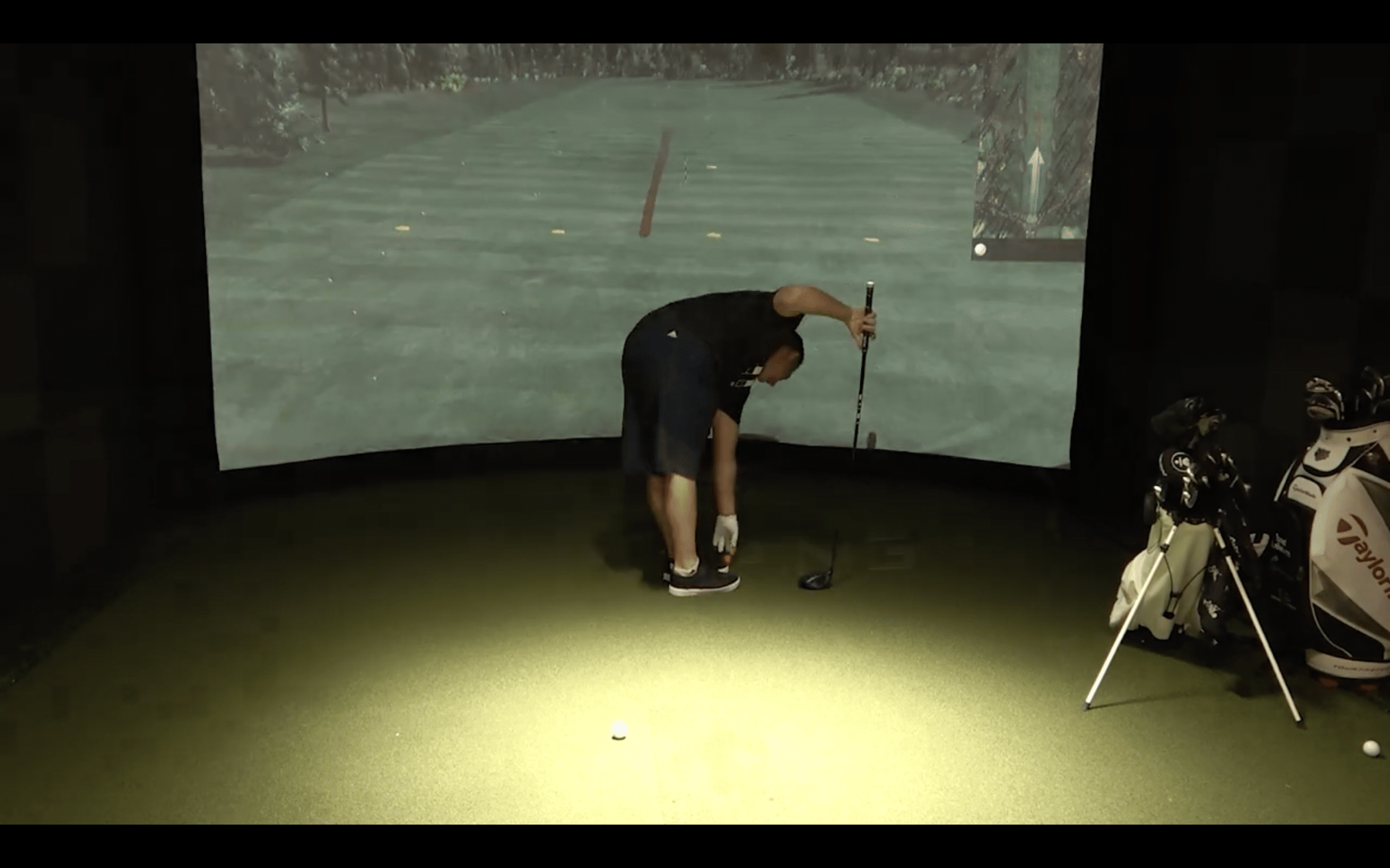 Golfer setting up in indoor golf simulator