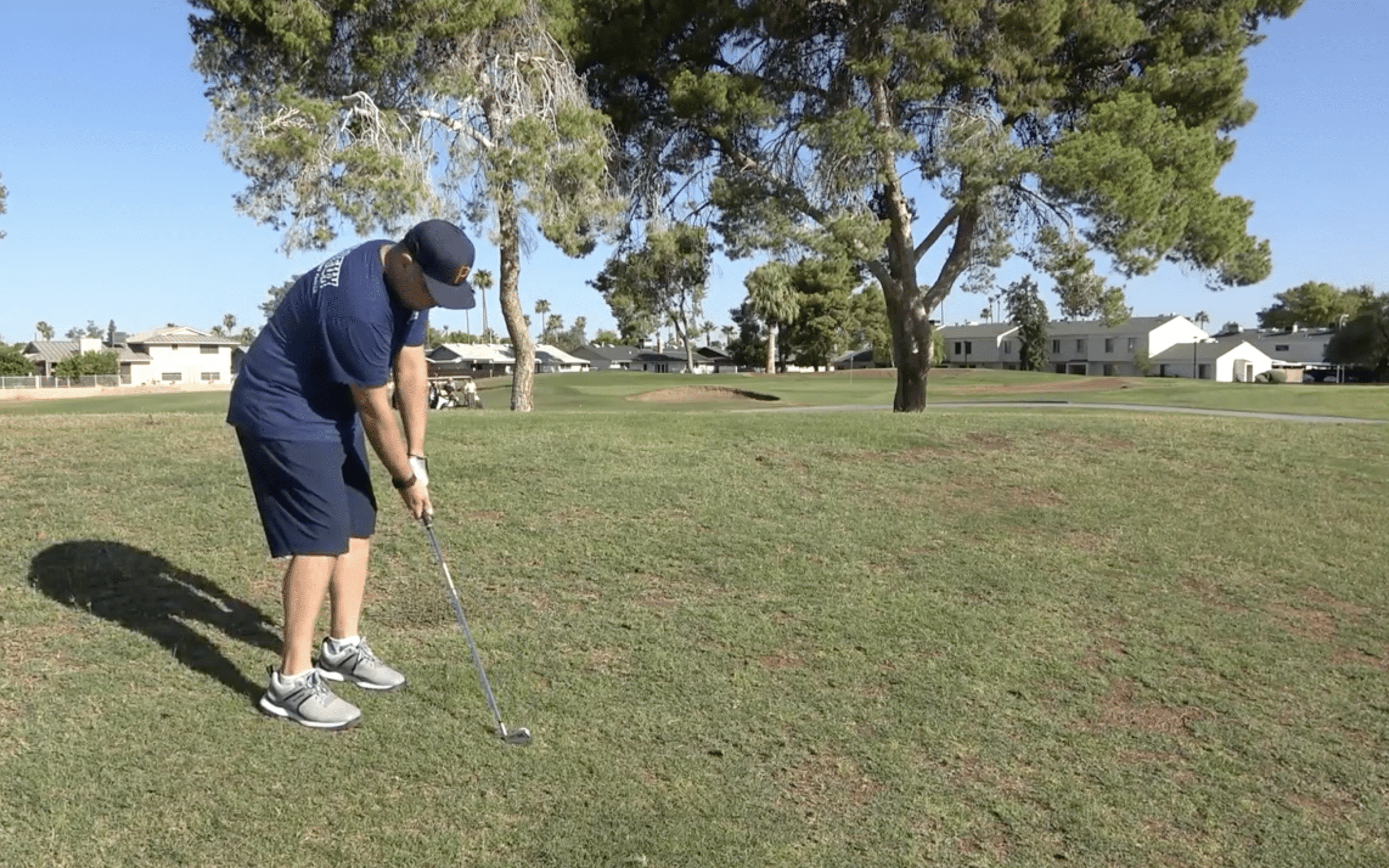 Golfer preparing to hit ball on sunny course