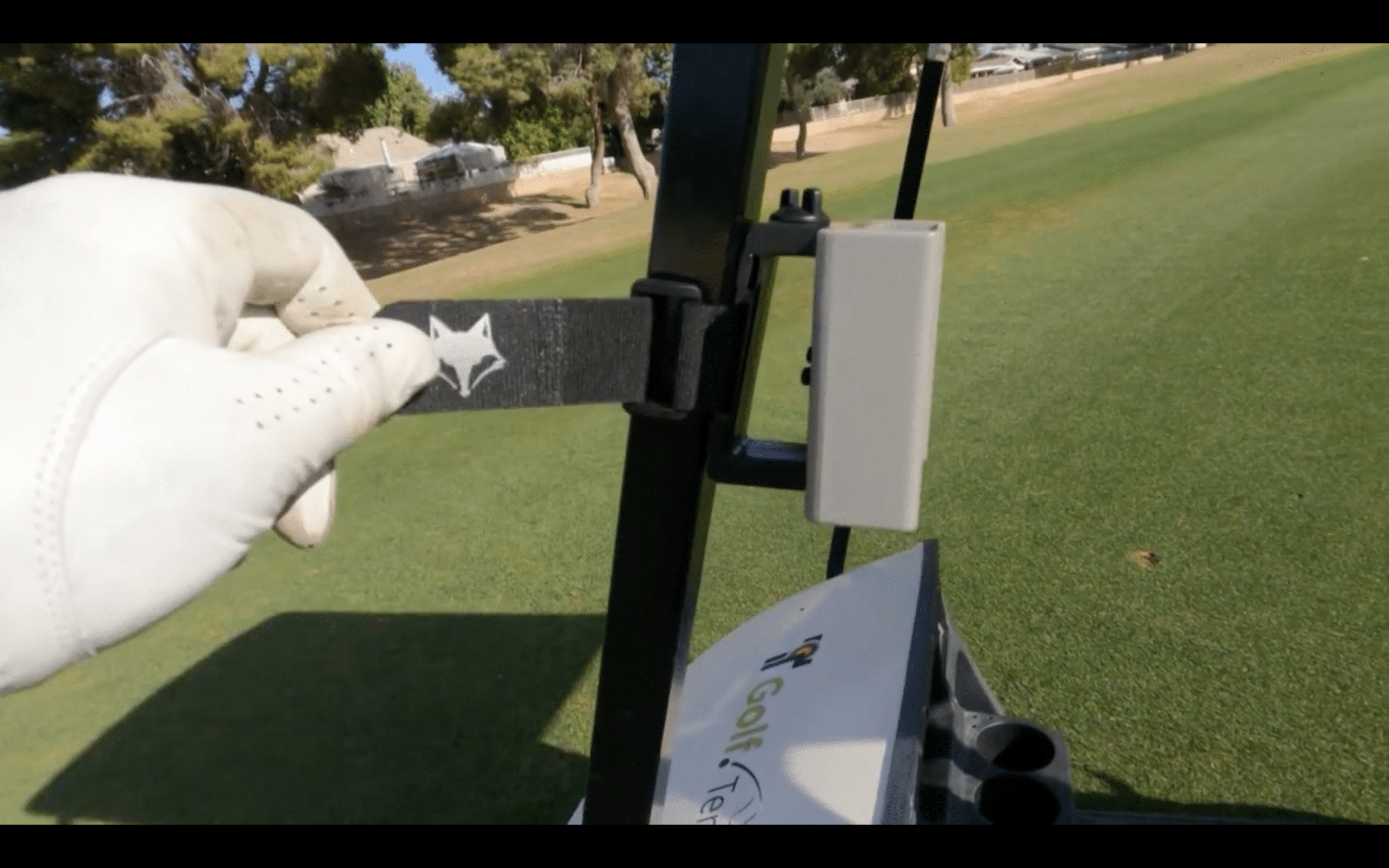 Golfer attaching strap to golf cart frame