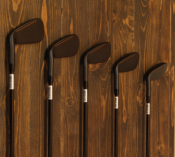 Black golf clubs hanging on wooden wall