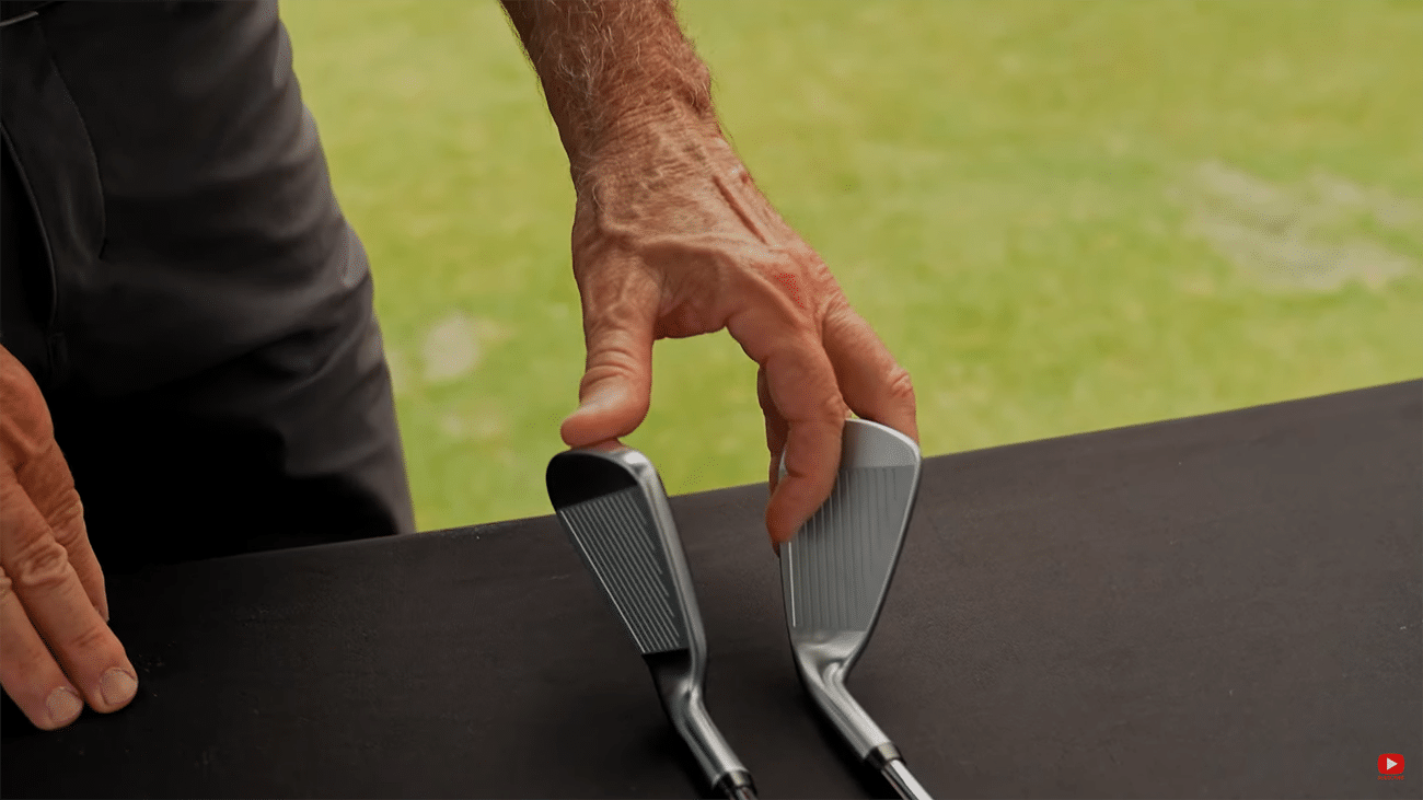 Person comparing two golf club irons.